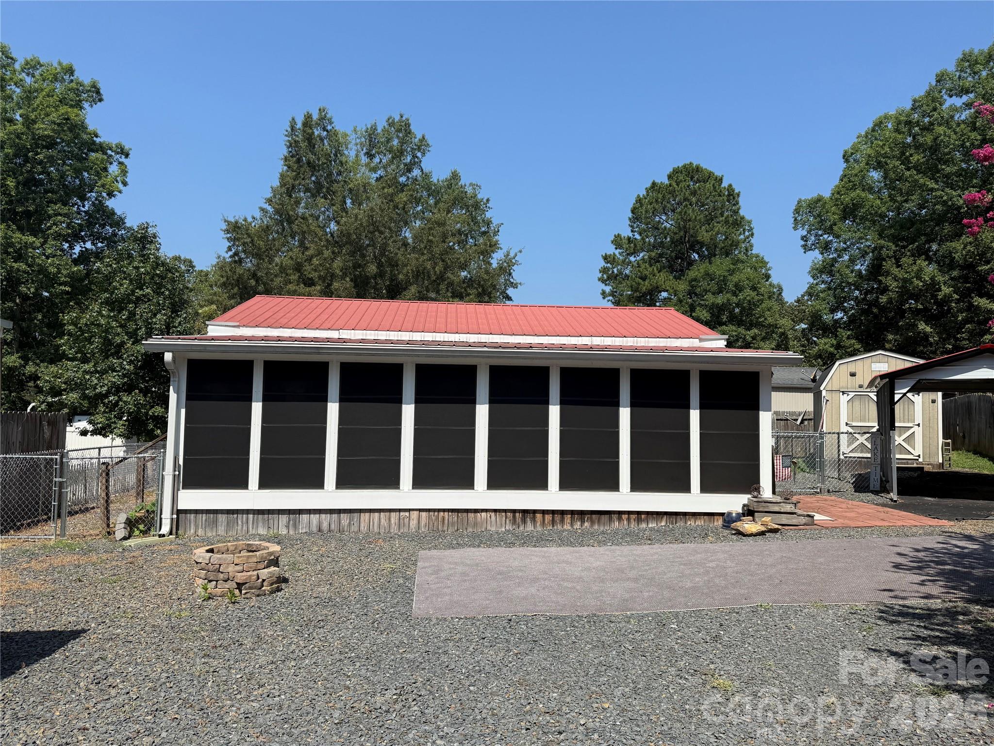 Welcome to one of my favorite units here in the park. Quiet, Cul-de-sac unit, flat, mostly gravel, low maintenance and near the entrance for easy access. 30' camper that has been completely redone, full addition with block foundation. Camper and addition have real HVAC. The enclosed porch with Easy Breezy Windows, new blinds and a mini-split for climate control comfort is currently being used as a TV room. Includes a table with chairs, oversized bean bag chair, rock n glide chair and a bungee chair. Large room with plenty of space for all your guests. Move into the added living room, with sofa, recliner, TV, table and trundle bed. Also in the addition is the primary bedroom with nice space and good storage. The camper is now a lovely kitchen with really nice appliances, updated bathroom with alcove tub/shower combo, new vanity and real potty. Small area with a twin bed for additional sleeping. 
Fenced back yard for your dogs. New flag pole. There is a carport for your car or boat. A shed in a box for your golf cart. A fully insulated building with power, water and a washer/dryer to remain and a loft. Great lot here in the park. Come and see if this can be your "Happy Place".
All buyers must be with a realtor to gain entry to the park.