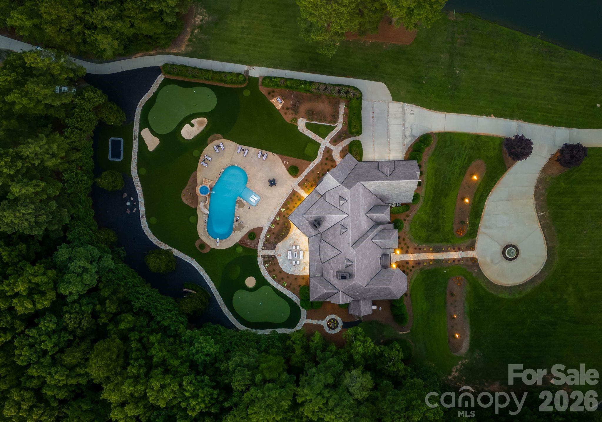 Beyond a gated entrance, a winding drive reveals one of the Charlotte region's most extraordinary private estates. A rare offering where timeless architecture, modern innovation, and extraordinary privacy converge, this magnificent estate spans 33.3 picturesque acres overlooking stocked ponds and rolling grounds teeming with wildlife. Encompassing more than 9,300 square feet, this meticulously renovated residence delivers an unrivaled lifestyle just minutes from Charlotte. Designed to impress while remaining effortlessly livable, the home features five bedrooms, four full and one-half baths, gracious entertaining spaces, multiple fireplaces, a luxurious primary suite, media room, bonus room, and an exceptional chef’s kitchen complemented by a fully renovated scullery and custom walk-in pantry. Throughout the home, every detail has been thoughtfully elevated—from refinished hardwoods and designer lighting to completely renovated baths with heated tile floors, frameless glass showers, custom cabinetry, and curated finishes. State-of-the-art technology seamlessly integrates throughout with a fully automated Control4 Smart Home system, motorized shades, whole-home audio, advanced security, Wi-Fi-enabled hot water recirculation, smart leak detection, and a backup generator providing peace of mind. The lower level is dedicated to recreation, featuring a custom home theater, Uneekor golf simulator, and private fitness studio. Outdoors, the estate transforms into a private resort with a spectacular saltwater pool and spa, outdoor kitchen, expansive patios, propane fire pits, built-in trampoline, and a remarkable 12,000-square-foot Scottish-inspired chipping and putting course overlooking the water. Automobile enthusiasts will appreciate the oversized garage featuring new epoxy flooring, Wi-Fi-enabled high-lift garage doors, and two professional-grade four-post vehicle lifts. Additional improvements include a premium slate roof, recently replaced windows, professionally designed landscaping and lighting, newly paved rear driveways, and exceptional mechanical upgrades throughout. Steeped in character and history, the estate was even featured during the production of 3: The Dale Earnhardt Story, adding another layer to its distinctive legacy. Offering exceptional privacy without sacrificing convenience, this extraordinary estate presents a once-in-a-generation opportunity to own one of Cabarrus County’s most remarkable luxury properties.