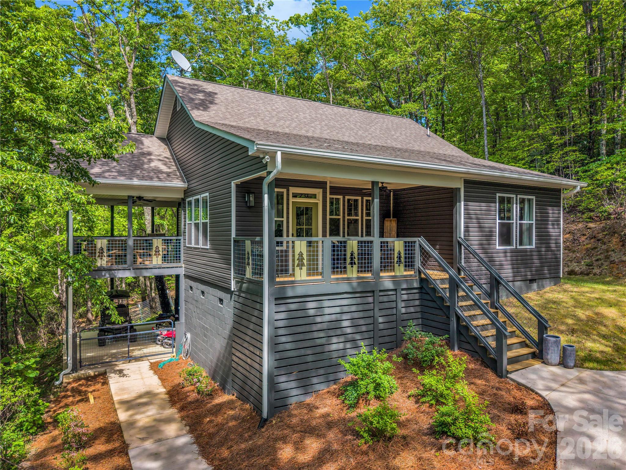 Nestled in the lush canopy of the exclusive Melrose Mountain subdivision, this 2023-built retreat offers the pinnacle of modern mountain living. The home welcomes you directly into a stunning gourmet kitchen designed for the culinary enthusiast, featuring an oversized social island and a premium appliance suite with a Bosch dishwasher and a professional 36-inch Forno stove w/ cafe doors and Forno refrigerator. Just beyond the kitchen, the open-concept layout is flooded with natural light, revealing an airy great room anchored by a warm gas fireplace. The main level is thoughtfully designed for convenience and flow, featuring two bedrooms joined by a shared Jack-and-Jill bath and a functional hallway laundry. Upstairs, the privacy continues with a third bedroom featuring its own private ensuite bath, creating a secluded getaway or secondary suite.
Outdoor living is maximized with a massive covered side deck—a private retreat in the trees ideal for alfresco dining or morning coffee as you enjoy the seasons unfold  —while a welcoming front porch provides a classic entry point to this light-filled contemporary gem. Residents of Melrose Mountain enjoy resort-style amenities, including two private lakes (one for swimming with a beach and one for fishing), a community dock, a picnic area, a clubhouse, and a tennis court that doubles for pickleball. Located just 30 minutes from the world-renowned Tryon International Equestrian Center and minutes from downtown Tryon’s boutiques, fine dining, and local vineyards, this home offers the perfect balance of Blue Ridge wilderness and luxury.