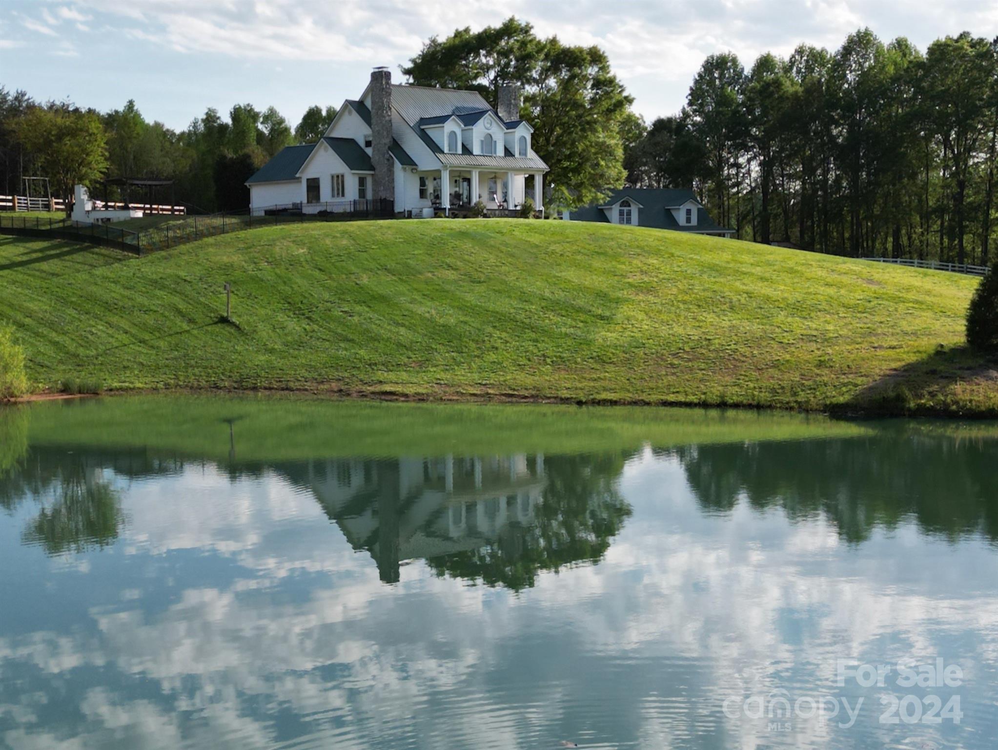 Welcome to your dream equestrian property in Tigerville! This stunning 13+ acre horse farm features a classic farmhouse with breathtaking Blue Ridge Mountain views. Situated amidst meticulously maintained grass pastures and overlooking a spring-fed pond, the farmhouse over 3700sqft, complemented by a 5000sqft center aisle barn. Conveniently located 40 minutes from Tryon International Equestrian Center, it offers proximity to top-notch venues. Inside, enjoy gleaming hardwood floors, a stone fireplace, and a spacious kitchen with granite counters. The main level master suite boasts a stone fireplace & luxurious ensuite bathroom. Downstairs, a flex room awaits, while upstairs, discover four additional bedrooms. Outside, entertain with an inground pool, jacuzzi, waterfall, firepit, and raised garden beds. Equestrian amenities include a barn with 5-6 stalls, riding arena, & round pen. Features include separate water heaters & septic systems, generator, RV hookups, and fiber optic internet.