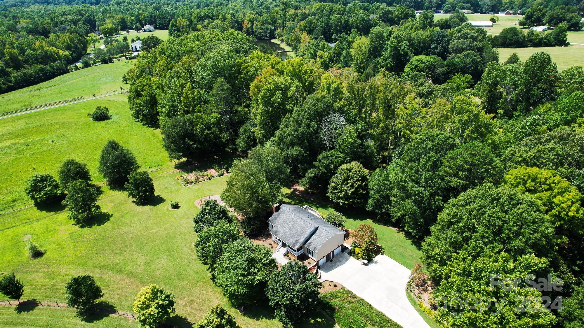 Wonderful, peaceful setting, yet so close to the conveniences in Clover, the town with LOVE in the middle! This delightful home sits on a picturesque 6.98 acres, complete with open pasture land, woods for leisurely walks, and the perfect pond for fishing or paddling your worries away. Move-in ready with numerous updates, featuring hardwood floors, a living room with vaulted ceiling, stunning views from dining and breakfast areas, three bedrooms, & two full baths on the main floor. Ideal for nature lovers, horse or gardening enthusiasts, this property offers a tranquil setting to observe wildlife, changing seasons, and engage in gardening activities. The oversized basement garage is wide & deep - can double as a workshop, while the bonus room & office area in basement provide flexible living space. The property boasts blackberry bushes, blueberry bushes, fig & pecan trees, and a separate garden area with a high fence to protect against wildlife intrusion. Award winning Schools & NO HOA!