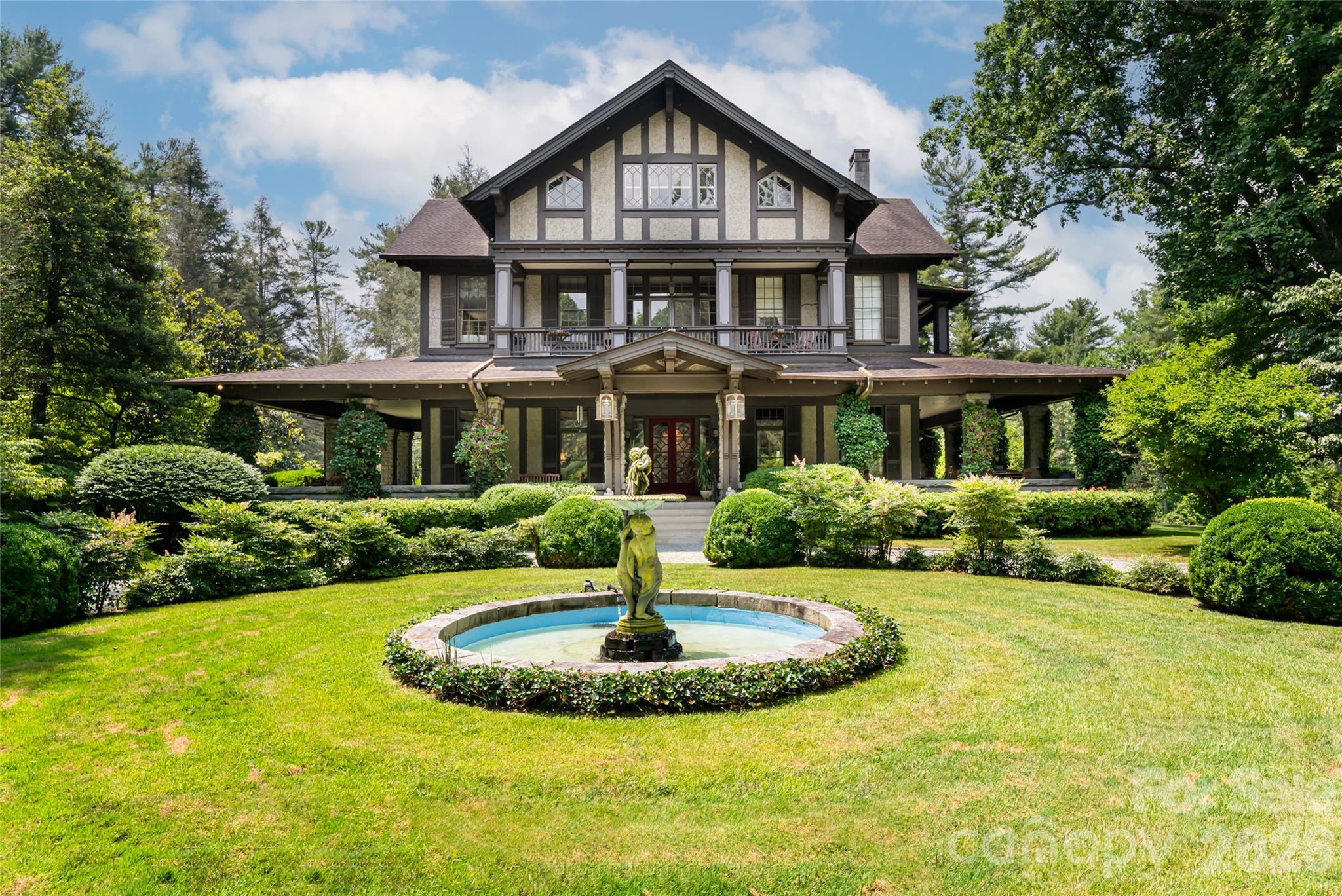 Teneriffe is one of Hendersonville’s extraordinary historic properties, an estate where history, architecture and opportunity converge in a rare and remarkable way. Originally constructed in 1855 as a Tudor Revival residence, the home was reimagined in 1903 by Richard Sharp Smith, supervising architect of the Biltmore Estate. With landscape input from the Olmsted firm, the property was shaped to complement its architectural beauty, establishing a setting steeped in provenance and timeless elegance. Set on 11.73 acres, the approach to Teneriffe winds along a leaf-canopied drive that opens to gardens, water features and the stately brick residence. The estate unfolds across rolling acreage, where pastures, walking trails and tranquil outdoor spaces form an enchanting natural setting. A historic barn recalls its agrarian heritage, while a separate log cabin offers endless possibilities for restoration, reinvention or flexible guest accommodations. Zoned for residential and commercial use, Teneriffe offers rare versatility. With a rich history as an active bed-and-breakfast, the property presents exceptional potential for a boutique hospitality venture, private retreat, event venue or simply as a legacy private residence. An additional 9.43-acre parcel (PIN 9567-20-4498) is also available, expanding the possibilities even further. The main residence is a showcase of grandeur and intimacy. A sweeping wraparound veranda welcomes you into a grand foyer, where light, scale and craftsmanship set the tone. Expansive entertaining spaces on the main level invite gracious gatherings and quiet reflection, with period details carefully preserved to honor the home’s heritage. The private primary wing is a sanctuary, complete with an executive home office, spa and the promise of seclusion. Two additional levels provide generous accommodations with multiple bedrooms and living spaces, offering flexibility for family, guests or creative repurposing. Each room reflects a chapter of the estate’s storied past yet stands ready to be reimagined for the future. Teneriffe is more than a property, it is a legacy. Rarely does such a distinguished estate, with architectural pedigree, historic significance and versatile potential, come to market. For those who value heritage while envisioning the future, Teneriffe offers an unparalleled opportunity to steward a landmark property and create a new chapter in its remarkable story.
