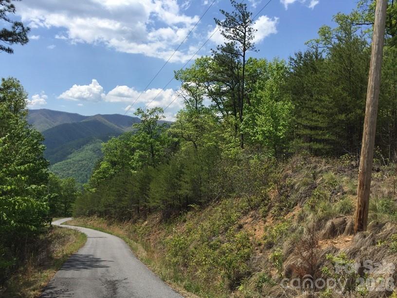 Rest in the shadow of the famous Cold Mountain and the Shining Rock Wilderness on this wooded 1.692-acre mountain homesite in Mountain Chalet Development with elevation, privacy, and filtered long-range mountain views already visible through the trees. Seller-provided historical view photos show the broader view potential that may be opened again with thoughtful, selective clearing. The property offers mature hardwoods, native rhododendron and mountain laurel, natural mountain terrain, and a quiet paved private-road setting above the valley. A prior expired septic/site evaluation is on file, showing a previously proposed 3-bedroom system area and a proposed drilled well location. This is not a current septic approval. Power is available along Lucerne Drive. Well and septic needed. Mountain Chalet offers paved private-road access, $100/year road maintenance, and no city taxes. Recorded CCRs/restrictions state an expiration date of January 1, 2025, and were not renewed. The yellow and white tape is only a guide and not a survey. Convenient to Canton, Waynesville, Maggie Valley, the Blue Ridge Parkway, Devil’s Courthouse, Mt. Pisgah, Cold Mountain, Shining Rock Wilderness, and more.