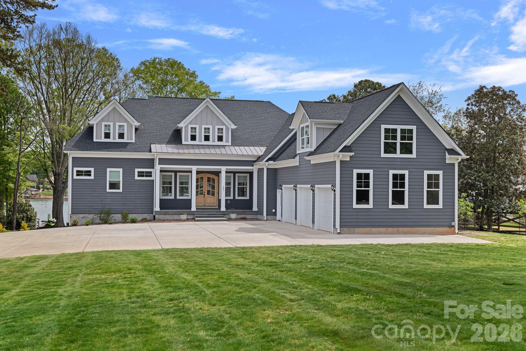This custom-built waterfront home with a 3-car garage offers a rare blend of refined craftsmanship, thoughtful design, and effortless lakefront living, all meticulously maintained and presenting like new. Ideally positioned along the shores of Lake Norman, the property showcases an exceptional connection to the water, highlighted by an impressive covered dock built in 2020 with a seating area, 10,000 lb boat lift, and two jet ski lifts, all set beside a rare sandy beach. Inside, the open-concept main living area is designed to maximize both comfort and views, featuring vaulted and coffered ceilings, abundant natural light, and panoramic lake vistas from nearly every room. High-end finishes, fixtures, and appliances are complemented by extensive custom-built-ins, including window seats perfectly positioned to take in the scenery and an impressive 86 custom drawers providing exceptional storage. The two-story home with lake-level basement includes a main-level primary suite with a private lake-view balcony, a vaulted great room with gas fireplace, and a beautifully appointed vaulted kitchen with a large island and breakfast bar, two new dishwashers, 6-burner gas range, beverage refrigerator, stainless refrigerator, walk-in pantry, and vaulted dining area, all designed to capture the water views. Upstairs, an inviting loft with a built-in reading nook is joined by three secondary bedrooms with lake views and a full bath. The walk-out basement expands the living space with a second kitchen, family room with woodstove, large bonus room with custom closet, one and a half baths, and generous storage. A massive workshop with its own driveway adds exceptional flexibility. Outdoor living is equally impressive, with a covered front porch finished in Pennsylvania bluestone, a spacious covered patio, and a covered deck with soaring vaulted ceiling and durable Wolf decking overlooking the lush lawn and lake, giving you fantastic water views from sunrise to sunset. The back and side yard feature lake-fed irrigation. There is also potential to create a private backyard retreat with a pool, spa, and sundeck, with documentation available. Enjoy the freedom of no HOA dues while remaining close to several clubs with additional lifestyle amenities, including Trump National Golf Club Charlotte, Lake Norman Golf Club, Lake Norman Racquet & Social Club, and Lake Norman Pickleball Club. Just a short drive to shopping, dining, and entertainment. With quick boat access to the main channel, this property offers an exceptional Lake Norman lifestyle where comfort and time on the water come together.