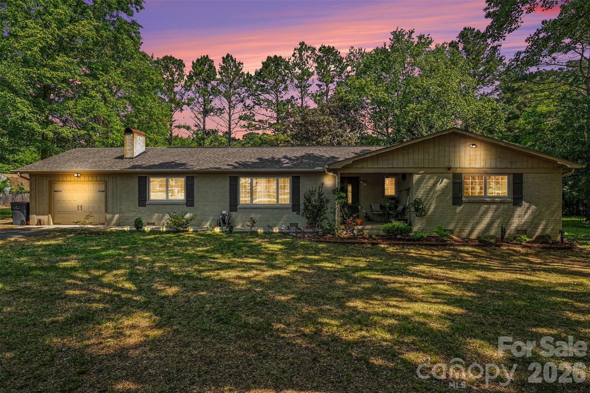 Tired of the noise and traffic? Have you considered a move to a more rural area? Check out this charming farmhouse-inspired renovation with timeless character and modern updates throughout. This classic brick ranch sits on a wide, beautifully landscaped lot framed by mature trees, offering both curb appeal and privacy.

Inside, you’ll find real wood flooring throughout (no carpet) paired with fresh, modern paint, updated lighting and fixtures, and elegant crown molding. The inviting living area features a cozy brick fireplace, while the flexible floor plan offers two separate living spaces with an open, easy flow perfect for everyday living and entertaining.

The kitchen is bright and stylish with white cabinetry, stone countertops, stainless steel appliances, and plenty of storage. A spacious primary suite provides room for a king-size bed, dual closets, and a beautifully renovated private bath. Both bathrooms showcase furniture-style vanities and thoughtful design.

Additional highlights include a walk-in laundry room with utility/pantry space, a deep one-car garage, and a backyard shed for extra storage. Enjoy multiple outdoor living areas within the fully fenced backyard, ideal for relaxing or entertaining.

Harrisburg offers a rare balance where you can enjoy a quiet, small-town atmosphere while staying just minutes from the energy of Charlotte and the speedway. Families are often drawn here for the top-tier schools like Hickory Ridge and the massive Harrisburg Park, which serves as the community’s heart with its splash pads, summer concert series, and famous July 4th parade. It’s the kind of place where you can grab a morning coffee at Rocky River and still be home in time to enjoy a large, wooded backyard in a safe, established neighborhood.