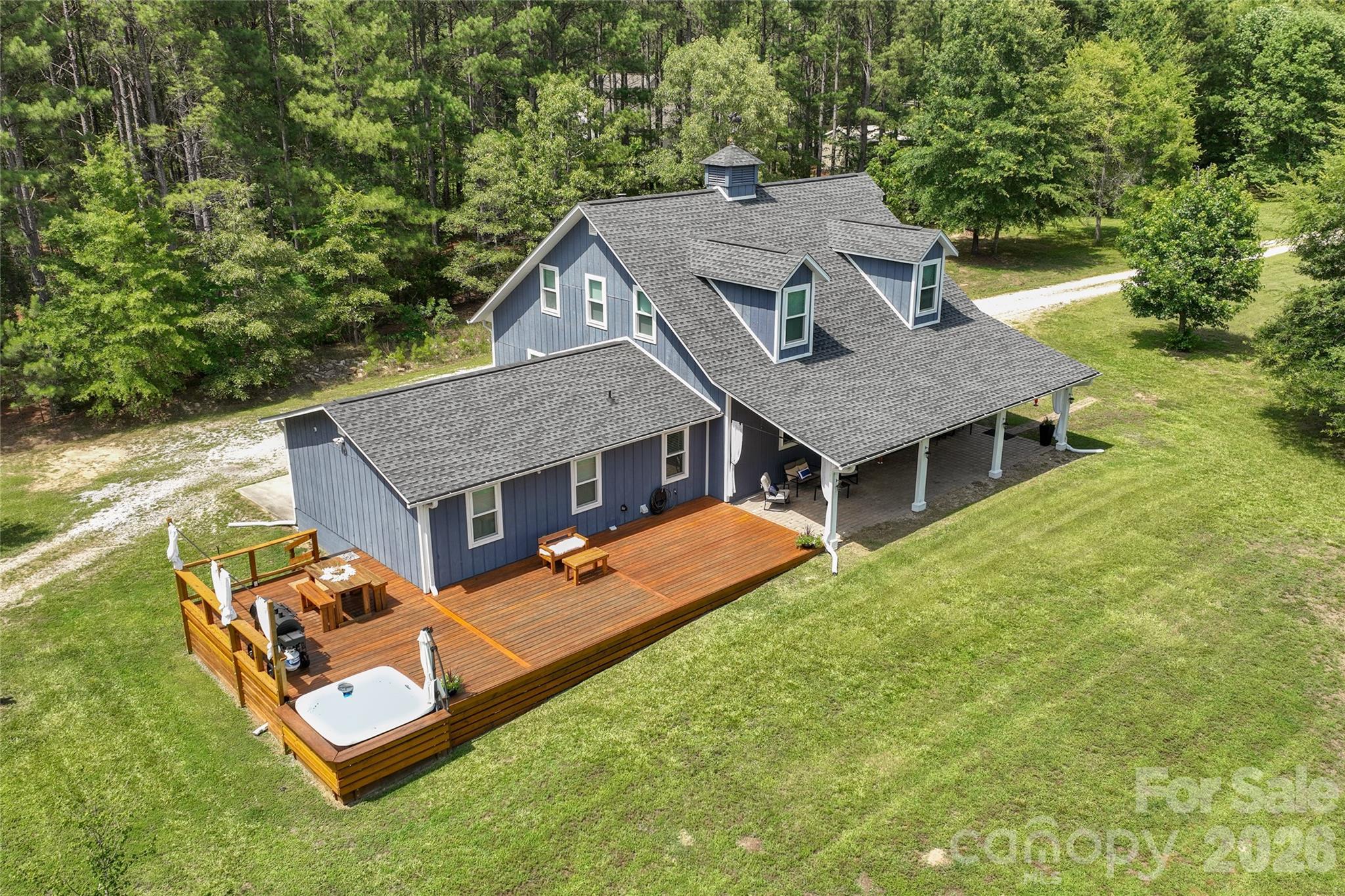 Home with +/- 5 ACRES?  It's HERE! Nestled just off desirable Sierra Road in York, SC, this one-of-a-kind Barndominium-inspired home blends rustic charm, modern comfort, and the freedom of country living on a beautifully shaped, nearly perfect rectangular homesite. Offering exceptional privacy and versatility, the property is ideal for those seeking a peaceful retreat, hobby farm, or equestrian lifestyle.

From the moment you arrive through the private electronic gate, you'll be captivated by the picturesque setting. A scenic pond with a charming cross bridge, mature trees, open green space, and a barn create a storybook welcome. Relax on the inviting covered front porch, entertain on the expansive wraparound deck, or unwind in the jetted spa while taking in the tranquil surroundings.

Inside, the spacious open-concept floor plan is designed for both everyday living and entertaining. The impressive great room features soaring ceilings, exposed beams, abundant natural light, and an inviting atmosphere that flows seamlessly into the dining area and oversized kitchen. The kitchen offers generous cabinetry, abundant counter space, a center island, and room for multiple cooks to gather with ease.

The spectacular second-floor owner's retreat is a private sanctuary unlike most. This oversized suite offers space for a sitting area, home office, or reading nook, along with attractive wood accents, built-in storage, and a spacious ensuite bath featuring a relaxing soaking tub.

Two additional bedrooms on the main level provide flexibility for family, guests, or remote work. A spacious laundry and utility room adds everyday convenience and additional storage.

Step outside to discover a property designed for enjoying the outdoors. Established fruit trees, a micro vineyard, and a thriving vegetable garden create an exceptional farm-to-table lifestyle. Whether harvesting fresh produce, tending the vineyard, fishing by the pond, or simply enjoying the peaceful landscape, or enjoying the jetted spa, every single day feels like a getaway!!!!