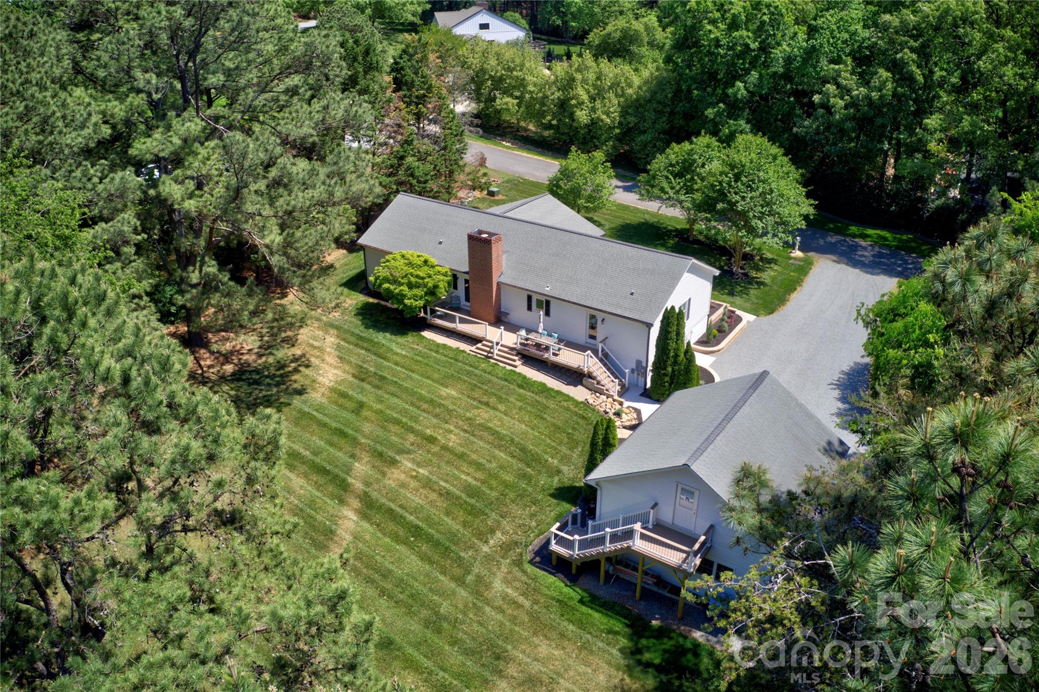 Scenic Grey Road sets the tone for this updated ranch nestled on over 1 acre in Greyland Hills — no HOA, no neighbors on top of you, and just over 2 miles from the heart of Davidson. Since purchasing, sellers have invested in extensive upgrades throughout: new windows and doors, roof replacement, encapsulated and conditioned crawl space, composite rear and front decking, French drain systems around the home and garage, refreshed landscaping and check out the retaining beds, updated kitchen and baths, new carpet, and refreshed lighting, hardware, and paint. The spacious primary suite offers a large walk-in closet and renovated bath. The encapsulated and conditioned crawl space doubles as excellent dry storage. Front porch and back deck are prime spots for the wildlife this private, wooded setting naturally attracts. The real showstopper for car enthusiasts, craftsmen, and hobbyists: a detached 2-car garage with 635 sq ft on the main level featuring a built-in workbench, steel I-beam for heavy lifting. A private exterior entrance leads to 438 sq ft of unfinished upper level — a blank canvas ready to become a workshop, studio, home office…you decide what it becomes! A large gravel drive extends along the left side of the garage for added parking and storage flexibility. Front porch, back deck and stairway to garage 2nd level all composite material for lower maintenance. Are you ready for some rural peace with town convenience, and room to breathe? Schedule an appointment today to see this amazing Davidson property.