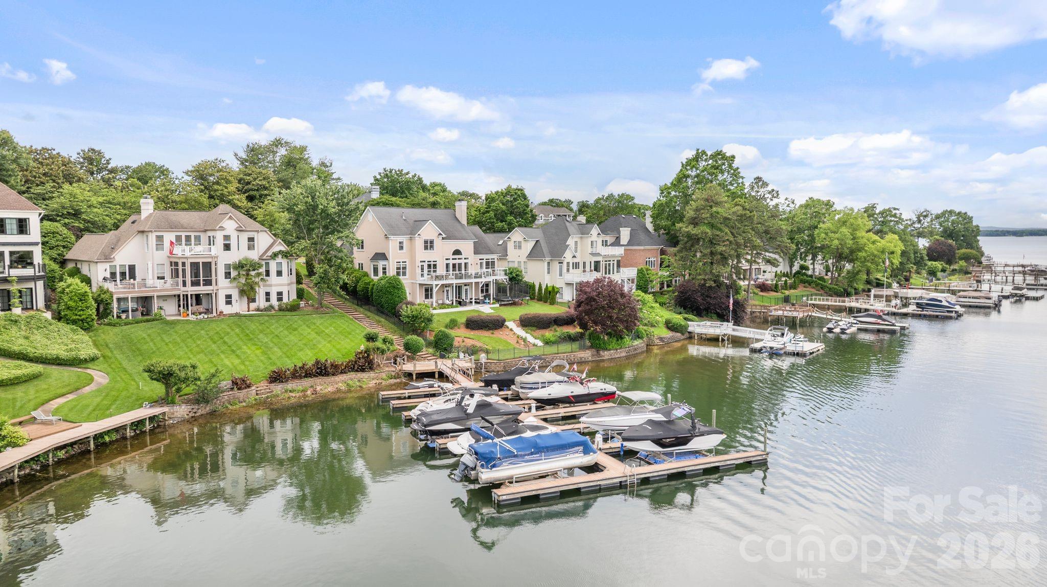 Stunning lakefront home in The Peninsula with wide Lake Norman views and boat slip with lift. Tucked at the end of a quiet cul-de-sac, this beautifully updated residence is designed to maximize seamless indoor-outdoor living with expansive walls of windows framing breathtaking water views throughout the main living areas. The renovated main level features a chef’s kitchen with premium Thermador appliances, open-concept living spaces, and a luxurious primary suite with updated spa-inspired bath and stunning lake views. Step outside to an expansive terrace perfect for entertaining or relaxing lakeside. Upstairs offers two bedrooms plus an optional 6th bedroom/bonus room. The finished walk-out basement includes two additional bedrooms, full bath, and versatile wet-storage room with additional laundry ideal for lake gear and storage. Flat manicured backyard with direct lake access and boat slip just steps away. Room for a pool with preliminary PPOA approval. Golf cart to The Peninsula Golf Club to enjoy golf, tennis, pickleball, fitness center, pool, and clubhouse amenities (membership separate). Rare opportunity to enjoy refined waterfront living in one of Lake Norman’s most desirable communities.