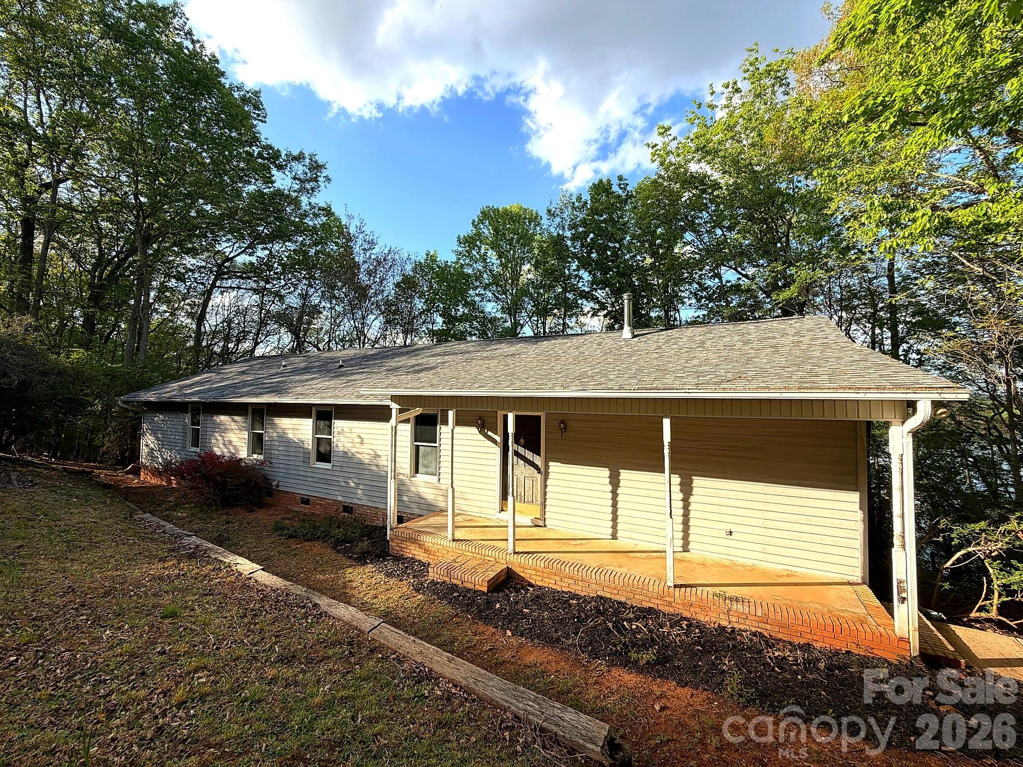 Escape the everyday in this charming home nestled among mature hardwoods with direct lake access and unmatched seclusion. A winding walkway through a lush tree canopy welcomes you home, while large windows throughout frame stunning wooded views.

Enjoy vaulted ceilings, a spacious living room opening to a private deck, and a well-appointed kitchen with custom cabinetry. A flex room with custom built-in bookshelves makes a perfect home office or library. Generously sized bedrooms include a primary suite with sitting area and a walk-in closet.

Outside, a private wooded staircase leads to your own dock — perfect for fishing, kayaking, or simply soaking in the open water views.

Move-in ready with great opportunity to add your personal touch, this lakefront retreat is a rare find.