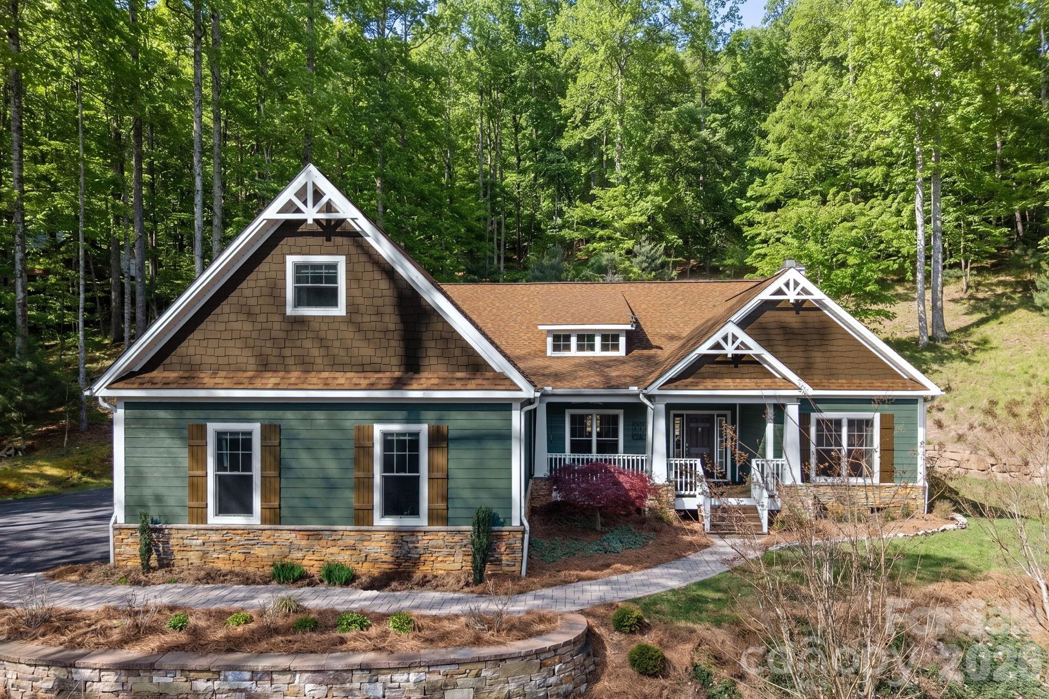 Discover refined mountain living at 455 Blue Mist Way, a beautifully crafted Arts & Crafts home set against the natural backdrop of the Pisgah National Forest. Offering over 3,100 square feet, this property delivers the ease of true one-level living with a versatile upper-level suite ideal for a fourth bedroom, guest retreat, or private bonus space. This home offers the perfect balance of seclusion and convenience just minutes from Asheville’s vibrant dining, arts, and entertainment scene. Located within a private gated community, residents enjoy exclusive access to resort-style amenities including a pool, sports courts, and scenic paths, perfect for staying active or unwinding close to home. Step out your door and onto nearby hiking trails, or relax in your own private sanctuary. The main living area is defined by vaulted ceilings, abundant natural light, and a warm, inviting atmosphere centered around the fireplace. Hardwood floors extend throughout the main living area, while the kitchen is thoughtfully designed with an expansive island, stainless appliances, a dual-fuel range, and a custom tiled backsplash that adds a refined layer of detail. The primary suite offers a spacious retreat with a beautifully finished bath featuring heated tiled floors, a freestanding soaking tub, a walk-in tiled shower, dual vanities, and a custom walk-in closet. Additional main-level bedrooms provide flexibility for guests, a home office, or additional living space. A light-filled screened-in 3-seasons sunroom offers a quiet place to unwind while overlooking the natural surroundings. The home backs up to the Pisgah National Forest, providing a unique sense of privacy, complemented by winter mountain views. Set on a wooded lot with very little grass to maintain, the property offers a peaceful, low-maintenance setting. The three-car garage provides exceptional space for vehicles, storage, or outdoor gear. A whole-house generator adds an extra level of peace of mind, while a new HVAC system installed in March 2026 adds to the home’s comfort and efficiency. A rare opportunity to experience privacy, quality, and convenience in a sought-after South Asheville location.