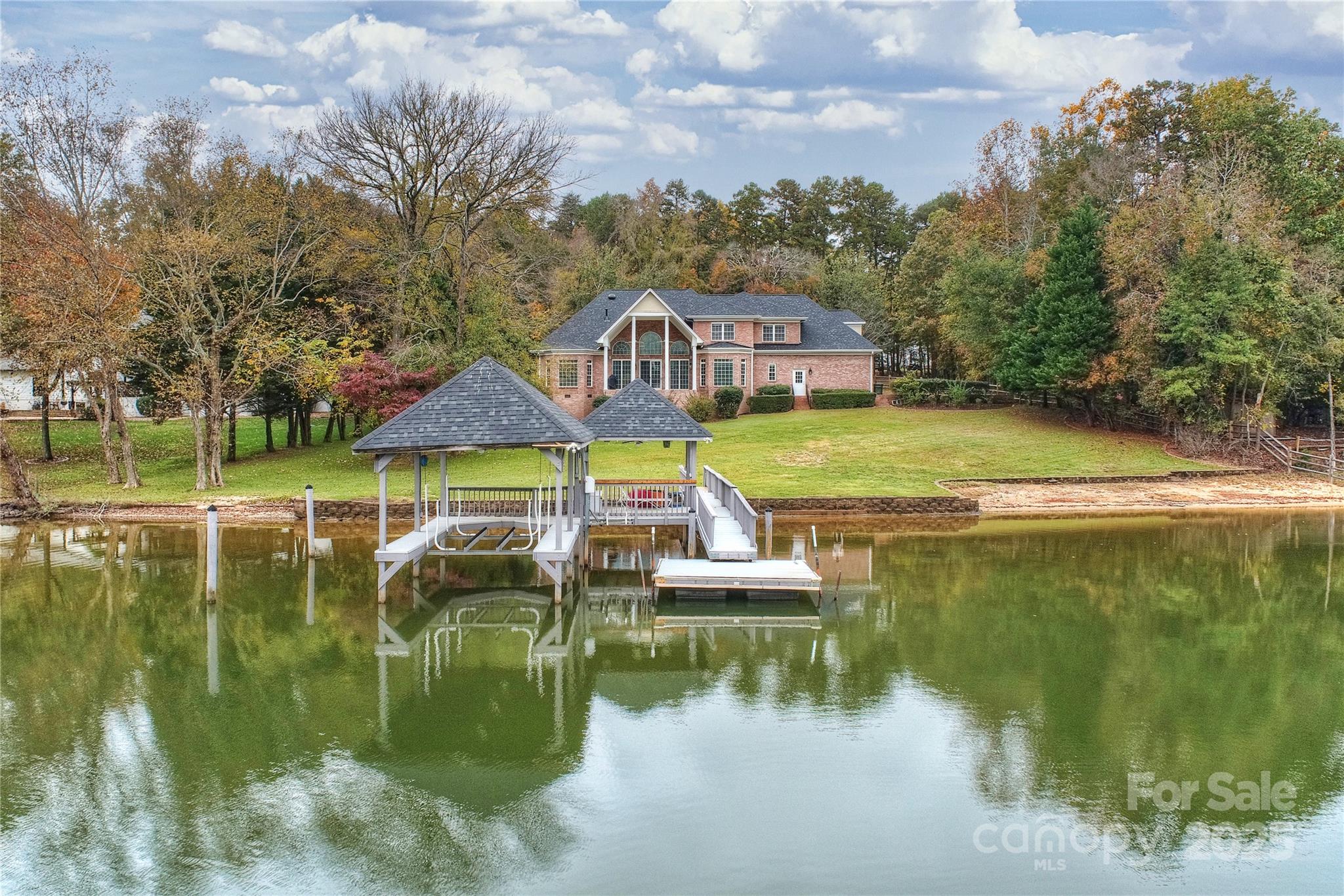RARE FIND - like NEW lake home! Custom built, full brick w/breathtaking views of Lake Wylie, situated on a spacious hard to find flat lot in desirable Fort Mill. Meticulously renovated from top to bottom, this beautiful home welcomes you w/a soaring 2-story foyer + curved staircase, formal dining, private office & 2-story great rm w/unmatched views, built ins & gas fireplace. Kitchen w/huge center island, new appliances, abundant cabinets & walk in pantry. Primary suite located on main w/2 walk-in closets & a stunning bath w/separate vanities, freestanding tub & oversized tile shower. 3 oversized BRs/2 bths up incl 1 BR w/en-suite, sitting area & walk-in cedar-lined closet. Lg bonus rm w/walk-in closet. Solid wood floors throughout, designer lighting & neutral paint. Newer roof & HVAC. Unwind on the covered rear porch overlooking the lake. 3-car garage + workshop offers space for projects & storage. Private dock w/covered boat lift + jet ski lift & jet ski launch + a sandy beach area!