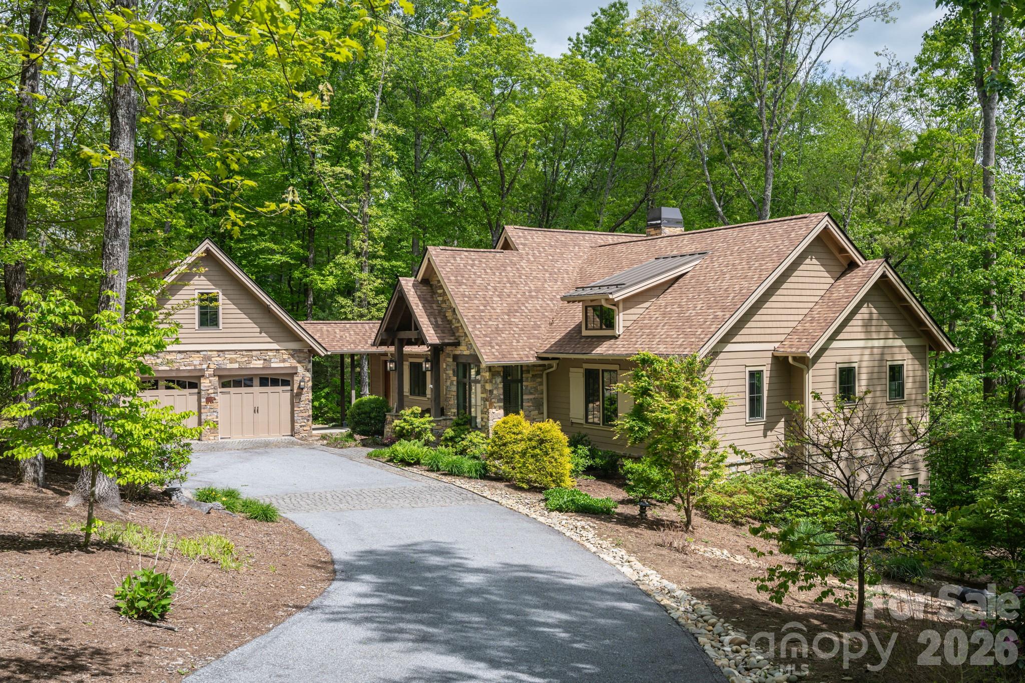 Tucked into 1.43 wooded acres in the gated mountaintop community of Grand Highlands at Bearwallow Mountain, this Energy Star Certified, 3 bedroom + Den with 2.5 bath home offers something special: peaceful tranquility, the beauty of nature, and a floor plan thoughtfully designed for the way people actually live. Large windows across the width of the main level living area draw the forest in through every season. The cathedral ceiling in the great room amplifies this sense of openness, rising above a stone gas fireplace that anchors the space with warmth. The floor plan flows naturally from great room to dining area to kitchen: connected, spacious, and perfect for entertaining. The kitchen is well appointed with KitchenAid appliances including a gas countertop range, oven, and warming drawer; a granite island with seating for two, custom maple cabinetry, and a pantry that keeps everything organized. Off the dining area, a screened deck extends the home into the tree canopy with its own stone gas fireplace – a peaceful outdoor space. The spacious main-level primary bedroom features an ensuite bathroom with heated floors, a spa soaking tub, and zero-clearance shower. A sun-filled den on the main level provides a versatile bonus room, ideal as a home office, creative studio, or reading retreat. The laundry room and mudroom connect via breezeway to the two-car garage with a 221 sq ft workshop. Downstairs, two bedrooms, a full bath, and a generous family room with exterior access and covered patio offer flexibility for guests or family. You will also find a cedar closet, second walk-in closet, and 516 sq ft of unfinished basement space that offers the possibility of a finished fourth bedroom with ensuite bathroom.
Grand Highlands amenities include a lodge-style clubhouse with fitness center, event spaces, library, and community garden, plus a dog park, tennis and pickleball courts, and hiking trails with direct trailhead access near the property. Just 25–30 minutes to both Asheville and Hendersonville.