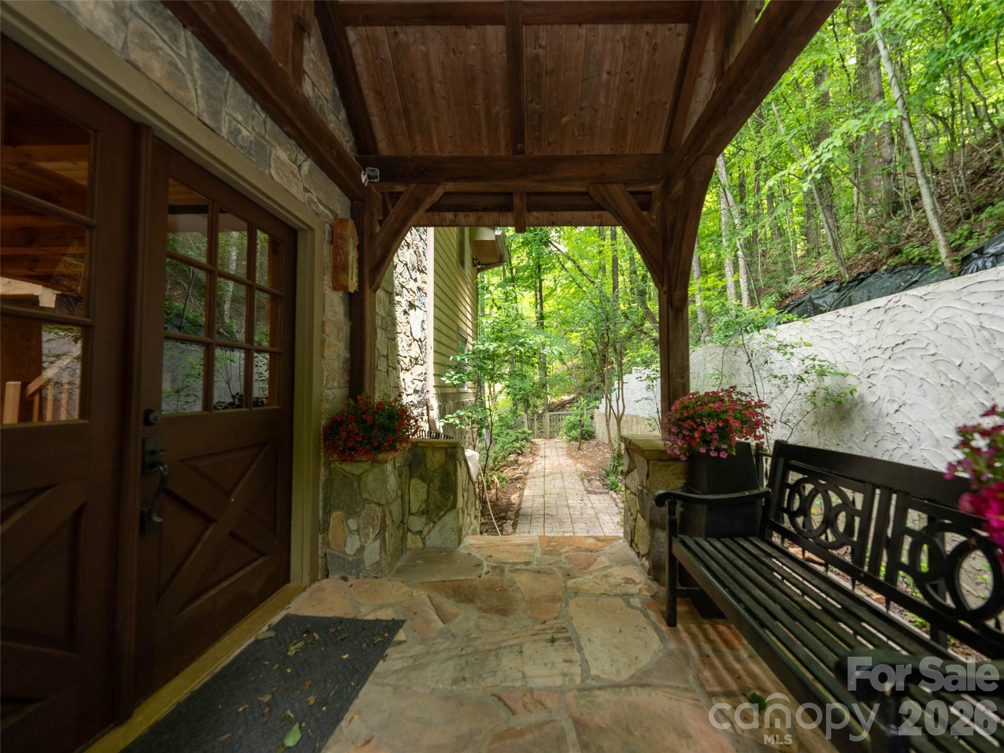 Stunning mountain retreat featuring stone and Hardie board siding with post-and-beam construction. Double front doors open to an open-concept layout with cathedral ceilings, hardwood floors, and abundant natural light. The living room centers around a cozy propane fireplace, while the sunroom offers incredible winter mountain views and private access from the primary suite. The kitchen and bathrooms feature slate flooring and granite countertops. The main-level primary suite fits a king bed, with a massive walk-in closet and a spa-like bath with soaking tub, walk-in shower, double vanity, and laundry chute. Upstairs includes a loft and two spacious bedrooms with large closets. The finished lower level, with chairlift access, is ideal for a guest suite, hobby room, or studio. A two-car garage offers space for a golf cart, plus a large storage room for outdoor gear. A perfect blend of luxury, comfort, and mountain charm.