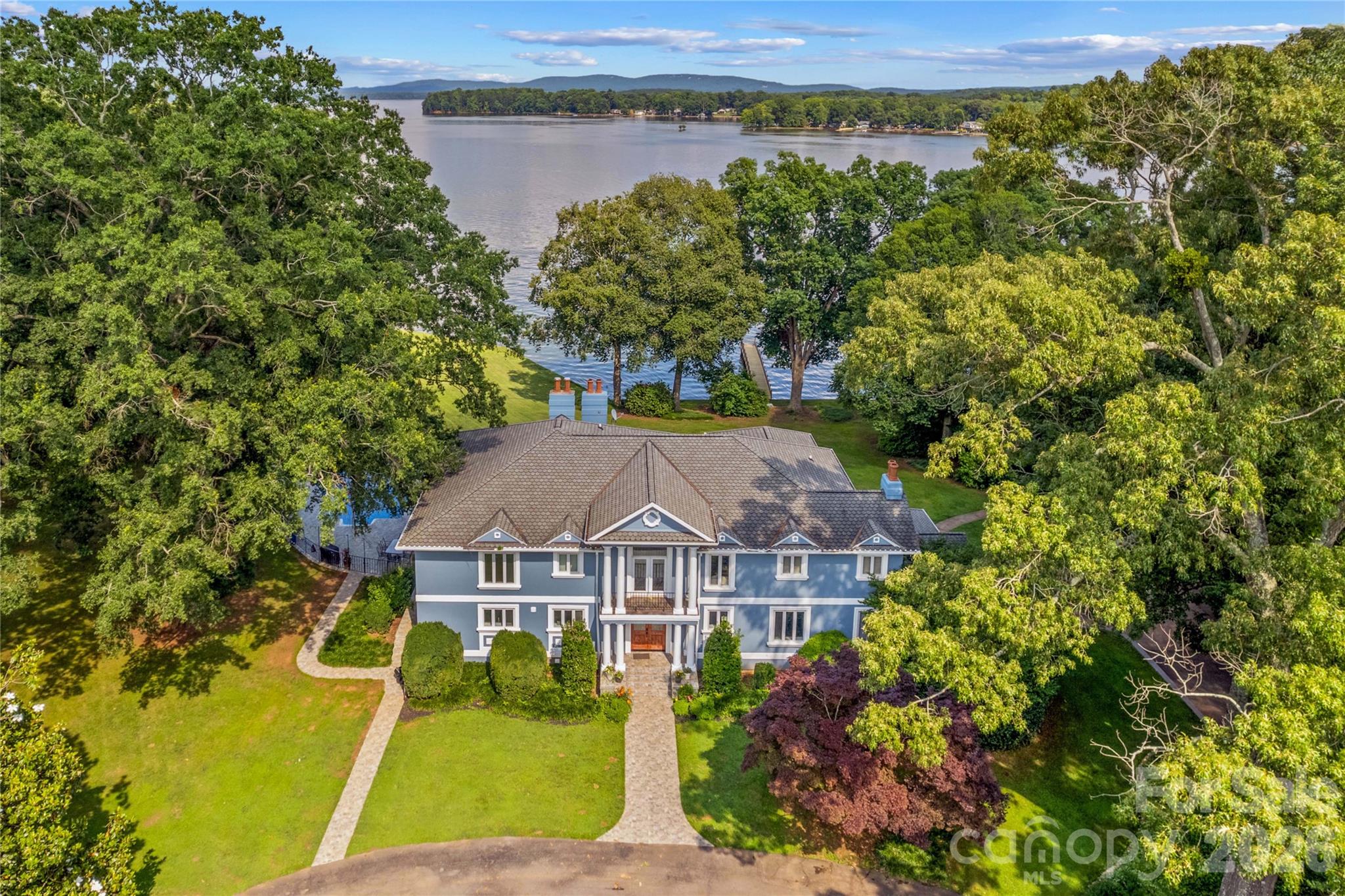 Spectacular lakefront living awaits on the shores of High Rock Lake! This extraordinary estate offers over 8,000 square feet of updated living space, designed to capture wide-range water views from nearly every room. Gated for privacy and set on 2.5± acres with almost 400 feet of shoreline, the property blends luxury, comfort, and resort-style amenities in a setting that is truly one of a kind. Step inside to discover an open floor plan where the chef’s kitchen—with striking granite countertops—flows seamlessly into the main living area framed by soaring floor-to-ceiling windows. The primary suite is a retreat of its own, featuring a sitting area and a private patio overlooking the lake. With 6 spacious bedrooms, 7.5 beautifully updated baths, multiple flex and office spaces, a loft, and even a dedicated dog grooming area, this home is designed for both elegance and function. Expansive outdoor living is at the heart of this property. Enjoy breathtaking views from the large veranda off the main level or entertain on the walk-out patio from the basement level. A stunning 745-square-foot inground pool with stone surround serves as the centerpiece of your private backyard oasis. The property also includes two private piers (432 sf and 580 sf) and is perfectly suited for multi-generational living. Additional features include a 3-car garage, circular drive, and meticulous finishes throughout. From its unmatched water frontage to its luxurious interior, this home is the ultimate High Rock Lake retreat.