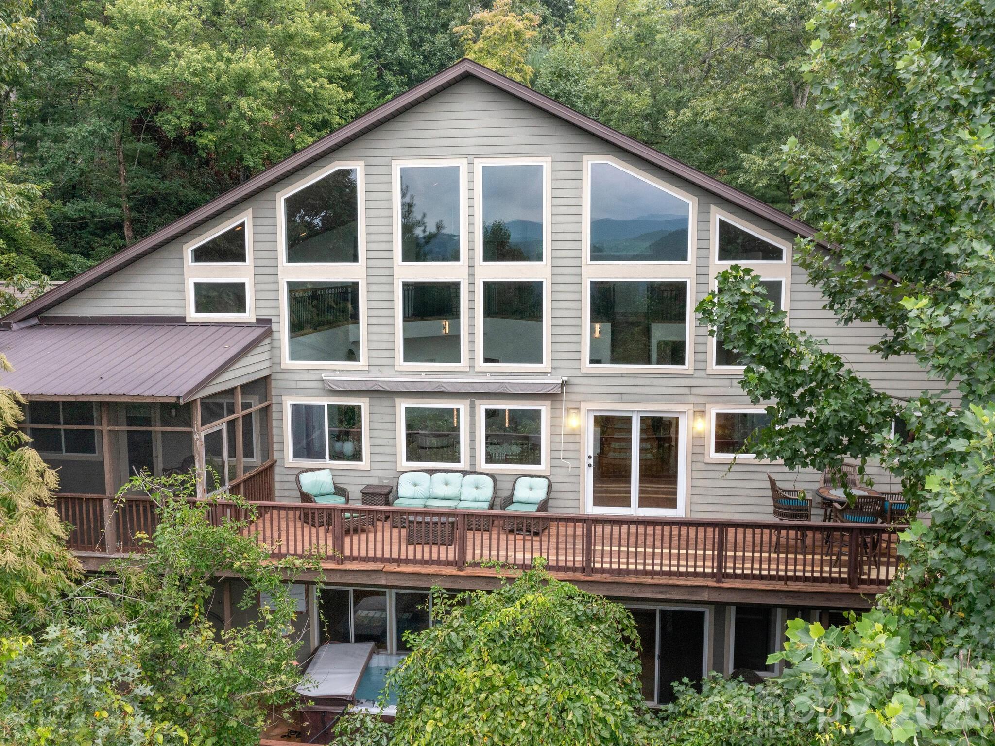 Where modern design meets mountain serenity, this inviting retreat captures the very best of Western North Carolina living. Thoughtfully designed for both everyday comfort and effortless entertaining, the home offers five spacious sleeping quarters spread across three levels—providing ample space for family and guests to gather while still enjoying privacy.

The main living area welcomes you with soaring tongue-and-groove cathedral ceilings, rich hardwood floors, and a cozy fireplace. Dramatic two-story windows frame sweeping mountain views, filling the space with natural light and bringing the beauty of the outdoors inside.

The primary suite serves as a peaceful sanctuary, complete with private access to a covered screened porch where you can start the day with coffee or unwind in the evening mountain air. A walk-in closet and spa-like bath with radiant heated floors, a garden tub, and a custom-tiled shower create a true retreat experience.

Upstairs, a sunlit loft overlooks the great room and captures stunning mountain scenery—an ideal place to curl up with a book, relax, or simply enjoy the ever-changing views.

The lower level offers exceptional versatility with a welcoming family room and fireplace, kitchenette, second laundry area, and flexible space perfect for a home office, gym, or hobby room.

Outdoor living is just as remarkable. An expansive deck and raised flagstone patio invite you to gather with friends or enjoy quiet evenings under the stars. Slip into the soothing hot tub, or follow the terraced path to a charming fire pit lounge nestled beside a tranquil crafted stream—an unforgettable setting for conversation, reflection, or making memories with guests.

Perfectly positioned for convenience, the property is located less than 10 miles from downtown Hendersonville, with nearby restaurants and shopping, and within easy reach of Asheville and the regional airport.

Furnishings are available, allowing for a seamless, turnkey experience if desired. Ideal as a primary residence, second home, or vacation rental, it also features a successful short-term rental history. Recent updates include a new electric hot water heater and heat pump, both installed in 2026.