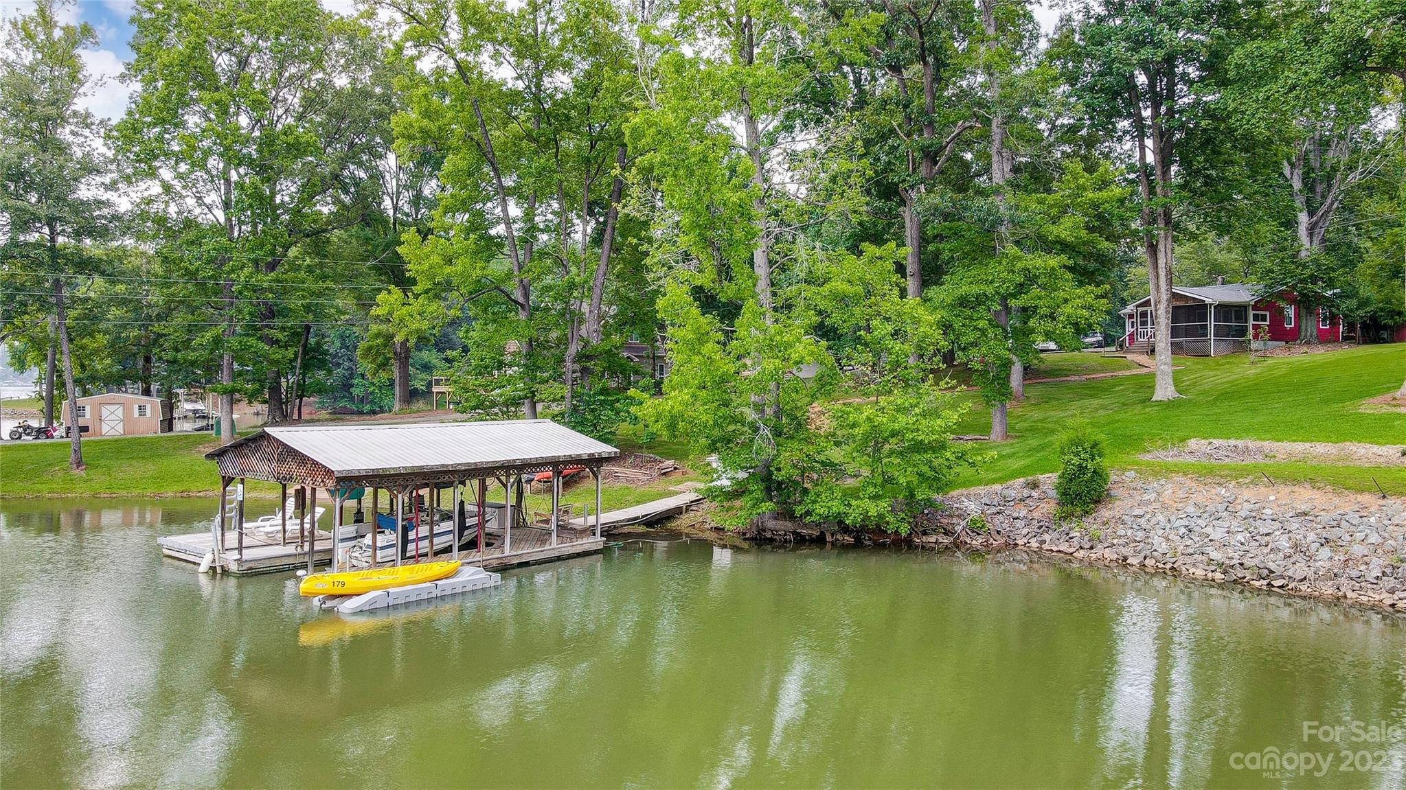 Designed to enjoy the outdoors, this classic waterfront cottage is on a gently sloping lot with mature trees, plenty of open lawn, beautiful natural shoreline, and offers a private boat ramp.  Nestled on a serene cove opening to the main channel, the best of both worlds. The Huge screened porch and covered dock are fantastic spots for outdoor entertaining or just to relax & take in the glorious views. Perfect for a weekend retreat or full-time living this waterfront gem is loaded with character and ready for you to put your personal stamp on it. Interior boasts one level living- kitchen opening to great room and dining area with plenty of windows to enjoy the lake views. Looking for peace, serenity & relaxation then this is the house for you!  Delivering that “away from it all” feeling yet only minutes to shopping, dining, 485, airport & Uptown Charlotte.