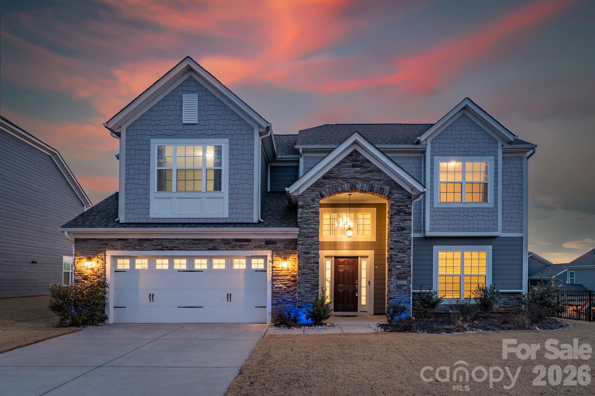 Exceptional, move-in-ready living awaits in this stunning 5-bedroom, 4-bath residence adorned with elegant stone accents, nestled in the highly sought-after Covington community—just minutes from Charlotte’s prestigious Ballantyne area, offering premier shopping, dining, and effortless highway access for an easy commute. A grand two-story foyer sets the tone, leading into a beautifully appointed main level featuring durable, designer LVP flooring and a sophisticated neutral palette throughout. The expansive formal dining room is ideal for hosting unforgettable gatherings. At the heart of the home, the gourmet kitchen impresses with crisp white cabinetry accented by antique gold hardware, wall ovens, gas cooktop with vented hood, oversized island with seating, sun-filled breakfast area, and a spacious walk-in pantry—perfect for both everyday living and elevated entertaining. The main level also offers a private guest bedroom with full bath, an inviting great room with a gas fireplace, and a convenient office nook. Step outside to unwind on the covered patio, creating a serene outdoor retreat ideal for morning coffee or evening relaxation. The upper level is highlighted by an expansive primary suite featuring a tray ceiling and a spa-inspired bath with a generous walk-in closet, dual-sink vanity, tiled shower, and a separate soaking tub. A conveniently located upstairs laundry room with a utility sink adds everyday ease. Three additional bedrooms and two full bathrooms complete the second level, offering ample space and comfort. Residents enjoy a community pool, clubhouse and playground.