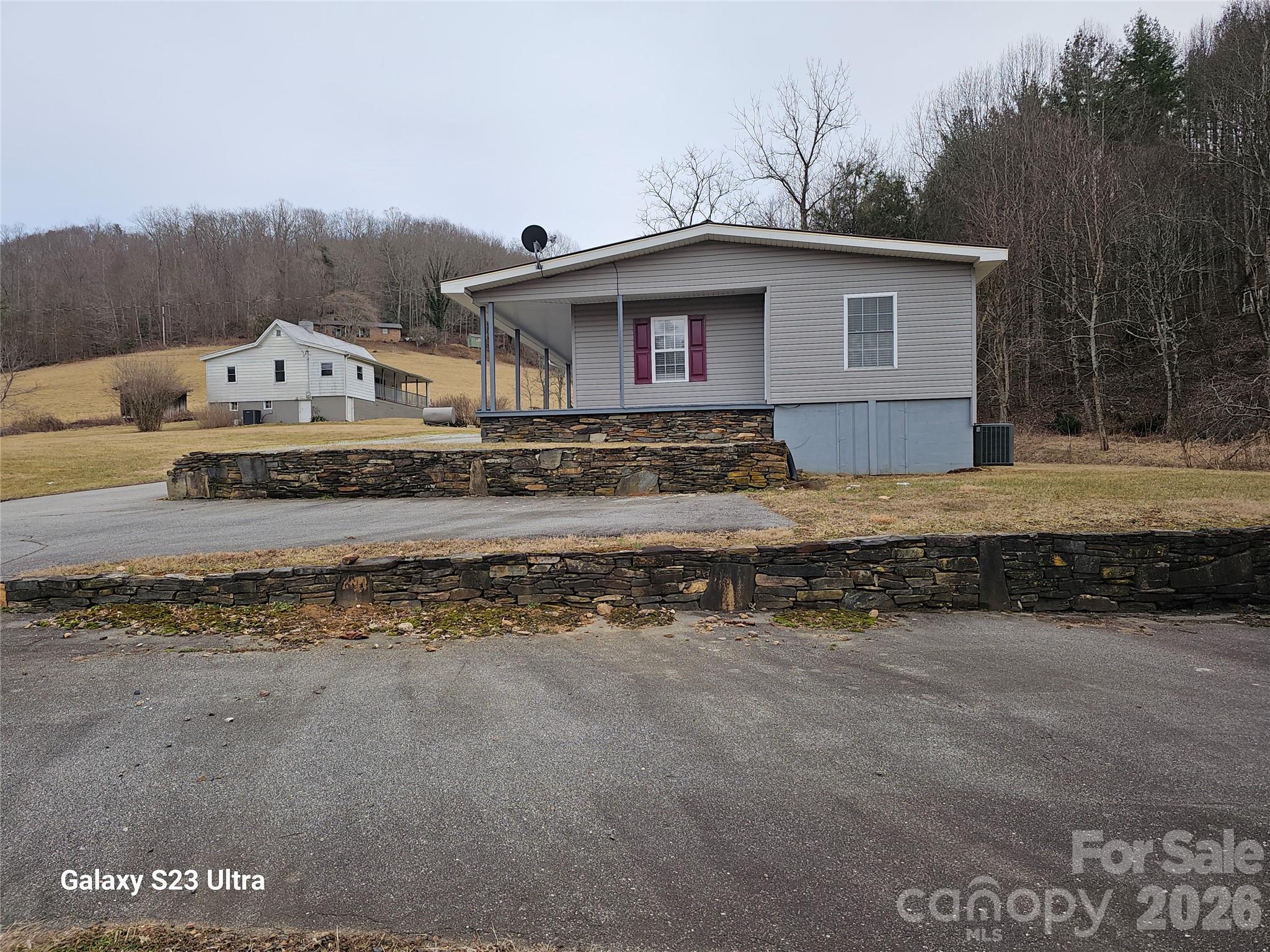 This beautiful move-in ready stick-built conversion home is situated in the Blue Ridge mountains of Bakersville, North Carolina.  The lawn and driveway are terraced with rockwork gathered from the nearby mountain. The windows, doors, and siding are replaced with conventional housing components and a metal roof has been added. A dining room, walk-in closet and flex room with exterior door (450sf) has been added.  The wrap-around 6’ wide porch is covered. A 16x24 workshop has siding and roof to match the house. The manufactured home core was built in the 1980s and the conversion was done in 1993. 

The second home (664 Water Street) was stick-built in 1917. The 1190 sf dwelling has 2 bedrooms, 2 bathrooms, dining room, den and a walk-in closet. The porch in the front is covered and the side porch is open. The HVAC was installed in 2023. This home is in good condition but needs some repairs. This is ideal for rental income, multigenerational living, a guest cottage, or an arts and crafts workplace.

A water well is shared between the two dwellings.

A 12’ right-of-way for the driveway will be added as part of the sale.