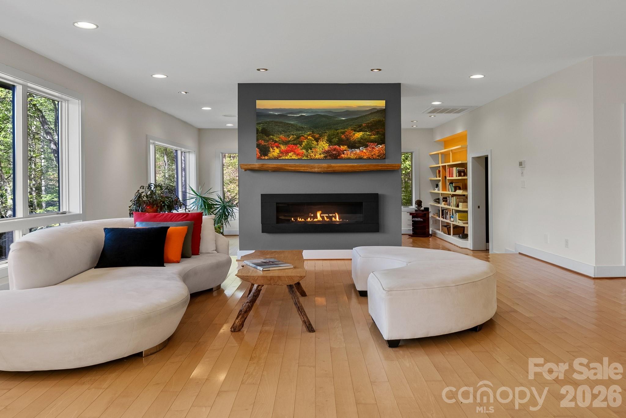 Designed for those who appreciate architecture, art, and the beauty of the natural world, this contemporary Green Built NC Certified home offers a rare fusion of inspired design, sustainable living, and elevated mountain lifestyle. Perfectly perched four acres just north of Asheville, the home overlooks a tranquil meadow where expansive windows frame ever-changing views of woodland, distant mountains, and open sky.  Bathed in warm southern light year-round, the interiors feel luminous and gallery-like…an ideal setting for art lovers and creatives alike. Thoughtful architecture celebrates light, space, and landscape, creating a home that feels both sophisticated and deeply connected to nature.

High-end finishes elevate every space, while the chef’s kitchen is designed for effortless entertaining and gathering. The spa-inspired primary en suite bath provides a peaceful retreat, with its deep, two seater soaker tub and heated floors. A gas fireplace adds warmth and ambiance on cool mountain evenings. Real maple floors run throughout, complemented by generous storage and well-designed closets that bring beauty and organization to everyday living.
A corner office on the second level captures sweeping meadow and woodland views, offering an inspiring place to work, read, or create. On the main level, the current TV room just off the main living area offers excellent flexibility. It could be thoughtfully reimagined as a main-level primary or guest suite by converting the private entrance area into walk-in a closet and expanding the adjacent half bath to include a shower or tub while still maintaining its functionality. Alternatively, this space would make an ideal artist’s studio, filled with natural light and creative potential or second office with its private entrance perfect for a home business, wellness studio, or guest workspace.
Outdoor living flows seamlessly onto durable composite decking, extending the living space into the surrounding landscape where sunrise light fills the meadow and evening sun sets quietly over the mountains.

Sustainability is artfully integrated throughout the home with GreenBuilt NC certification, an attached greenhouse, on-demand hot water system, whole-house filtration, and a 20,000-kw Generac backup power system, creating both environmental stewardship and peace of mind.
The oversized two-car garage offers abundant storage.  There is an additional, one acre buildable lot available for purchase providing a rare opportunity to create a second family home, guest residence, or private retreat.

Located within the welcoming Mountain Meadows community, residents enjoy shared organic gardens and neighborhood gatherings at the stylish Pavilion clubhouse. Outdoor enthusiasts will appreciate nearby hiking trails and easy access to skiing at Hatley Pointe Ski Resort.  Despite the peaceful mountain setting, convenience is close at hand. Charming Mars Hill is just 10 minutes away, Weaverville offers dining and shopping only 20 minutes from home, and the vibrant arts and culinary culture of Asheville is an easy 25 minute drive. I-26 and Asheville Regional Airport are also within easy reach.  

This is Western North Carolina living at its most inspired—where thoughtful architecture, sustainability, and mountain beauty come together to create a truly exceptional place to call home.  A property that offers more than a place to live…it offers a way to live.
