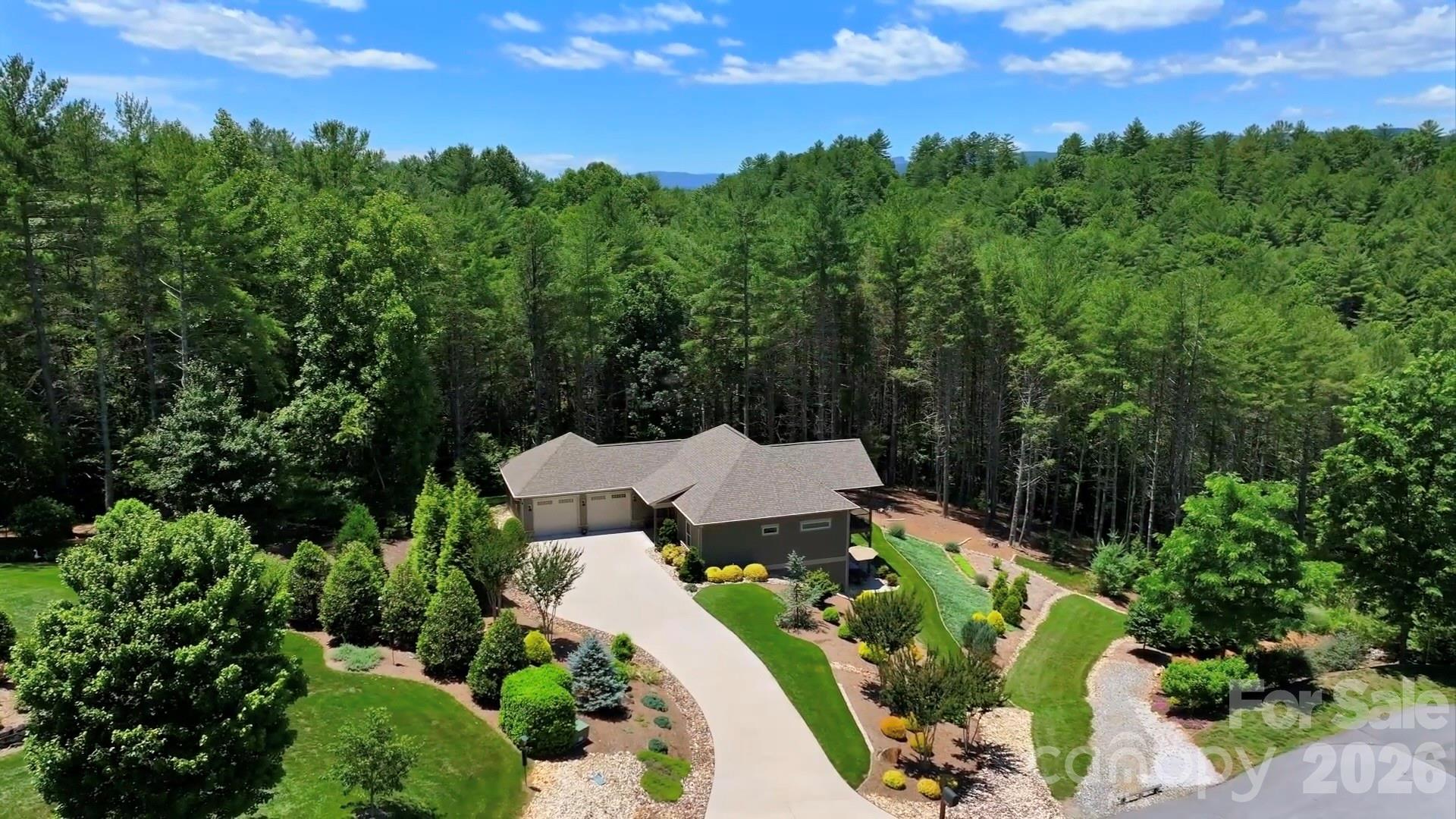 Discover your private sanctuary, 5515 Cedar Cove Way, at the renowned Coves Mountain River Club. This 3 BR 2.5 BA home on 2.67 acres is at the end of a quiet cul-de-sac. With a forest backdrop, the home's verdant landscaping of trees, ground covers, and river stone roots it naturally into its woodland surroundings.  2 levels of porches and deck are an indoor/outdoor retreat. Rarely do walk-out basements come with long range views—this home enjoys stunning, mountain vistas from both levels. Through the trees is a trail that winds down to a magnificent waterfall and on to the Johns River, by the vineyard, community garden, and River Barn Equestrian Center. Step inside and be immediately captivated by the Grandfather Mountain view, a living canvas right outside a wall of windows and glass that peak at the vaulted ceiling.  A gorgeous stone fireplace anchors the open floor plan.  The inviting back porch is your outdoor living room, with vaulted ceilings of tongue and groove wood and wood beams topped with a king post truss.  The porch is floored with low maintenance composite decking.  It is an ideal spot, any time of year, for soaking up the mountain air, watching sunsets and the change of seasons play out over the mountain ridgetops, and stargazing. 
The dining area is by double windows, with that incredible mountain view.  In the kitchen are tons of storage and workspace, custom cabinets, granite counters illuminated by under cabinet lighting, a travertine backsplash, and an island with seating. Appliances:  dual GE® wall ovens and gas cooktop, KitchenAid® refrigerator, ultra quiet Bosch Silence Plus 44dB dishwasher, and a Sharp automatic drawer microwave that slides out for easy top-down access. The walk-in pantry has built in shelves, and outlets for charging your cordless gadgets. The tranquil primary bedroom enjoys the Grandfather Mountain view too!  2 large windows face the view and over the bed, a clerestory (wide but shallow) window over the bed pulls natural light into the space.  The tailored spaces of the primary bath are your personal oasis for both waking up and winding down. Natural light fills the walk-in shower from a clerestory window at the top. The thick glass door keeps the shower space warmer and prevents water from splashing out.  Dual vanities shine with granite counters.   A linen closet adds essential storage.  Behind a space-saving pocket door, the expansive walk-in closet was designed for effortless organization, with tailored cabinetry, drawers, and versatile hanging bars.  Looking for 1-level living?  It’s here!  The main level also features a laundry room with sink and cabinet and easy garage access with no steps.
In the lower level den, 2 sliding glass doors open directly to the concrete patio and beautifully manicured lawn. Your senses are immersed in nature; smell the honeysuckle in the summer and the fallen leaves in autumn.  The den includes a wet bar, cabinetry, and a fridge, an ideal spot for entertaining, beer and a ball game, or binge watching your favorite new series.  Guests have 2 bedrooms to choose from.  The full bath is floored with ceramic plank tile that boasts a realistic wood finish and the tub/shower combo has striking linear tile. Also on the lower level is a flex room with built in workbench and shelves that can be a workshop, fitness room, or storage.  Double doors exit to a concrete pad and the back lawn.  There is room for your mower, UTV or other toys.
The Coves Mountain River Club is a 3,200 acre gated community on 5 miles of the Johns River. Amenities include a community wide trail system, river access areas, picnic pavilions. 2 Equestrian Centers. Community Garden. Vineyard. Dog Park. Mountain-top clubhouse, pool, fitness center, locker rooms, kitchen, viewing decks, fire pits and more! 500K acre Pisgah National Forest and Wilson Creek River Area across the road! 1.25 hour drive to Charlotte/Asheville, mins to Lenoir, Blowing Rock, Morganton, and Blue Ridge Parkway.
