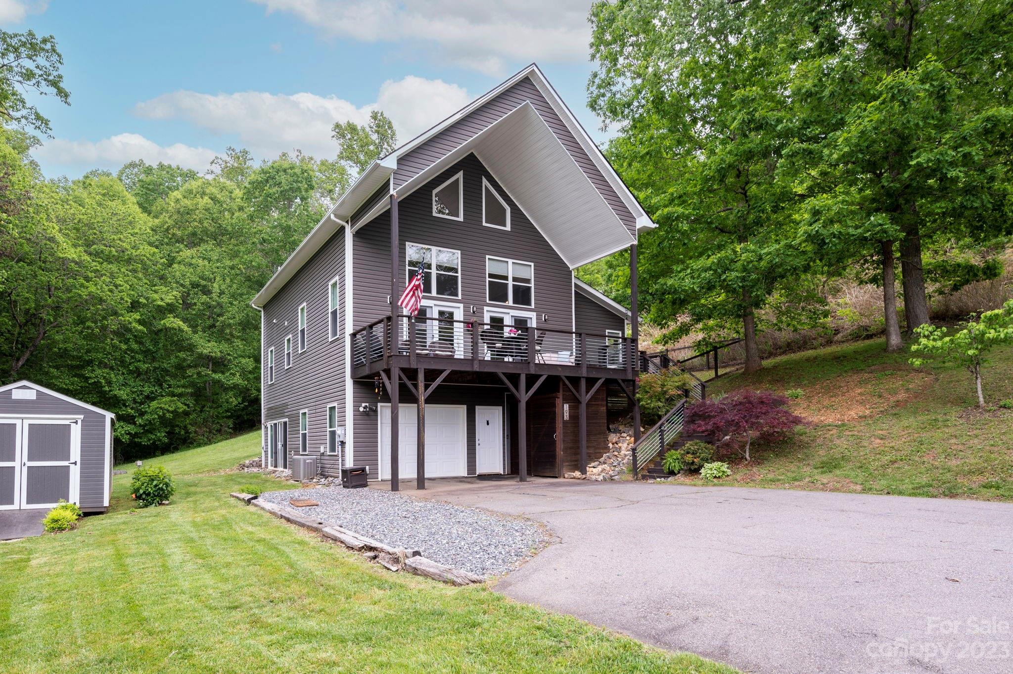 Peaceful and private, this low-maintenance, 1.5-story A-frame is the perfect contemporary mountain cottage, with fantastic views of the Blue Ridge from its fantastic covered front porch! Main living area features a wall of windows that floods the home with sunlight, plus a wood-burning stove for chilly evenings. The open-plan kitchen with stainless steel appliances is fit for a chef, and you're sure to enjoy the vaulted ceilings, luxury vinyl plank flooring, and more in the loft-style primary suite. There's also a finished lower level, perfect for a home gym, studio, office, or bonus room — and plenty of outdoor living in the fenced-in yard with storage shed, attached one-car garage, and flat, expansive driveway. Situated on a gorgeous and gentle 1.74 acres (two PINs: #9727452981 and #9727461015), only 5 miles from Mars Hill University, 20 minutes to Weaverville, and 30 minutes to vibrant downtown Asheville, this property would make an excellent primary residence or short-term rental!