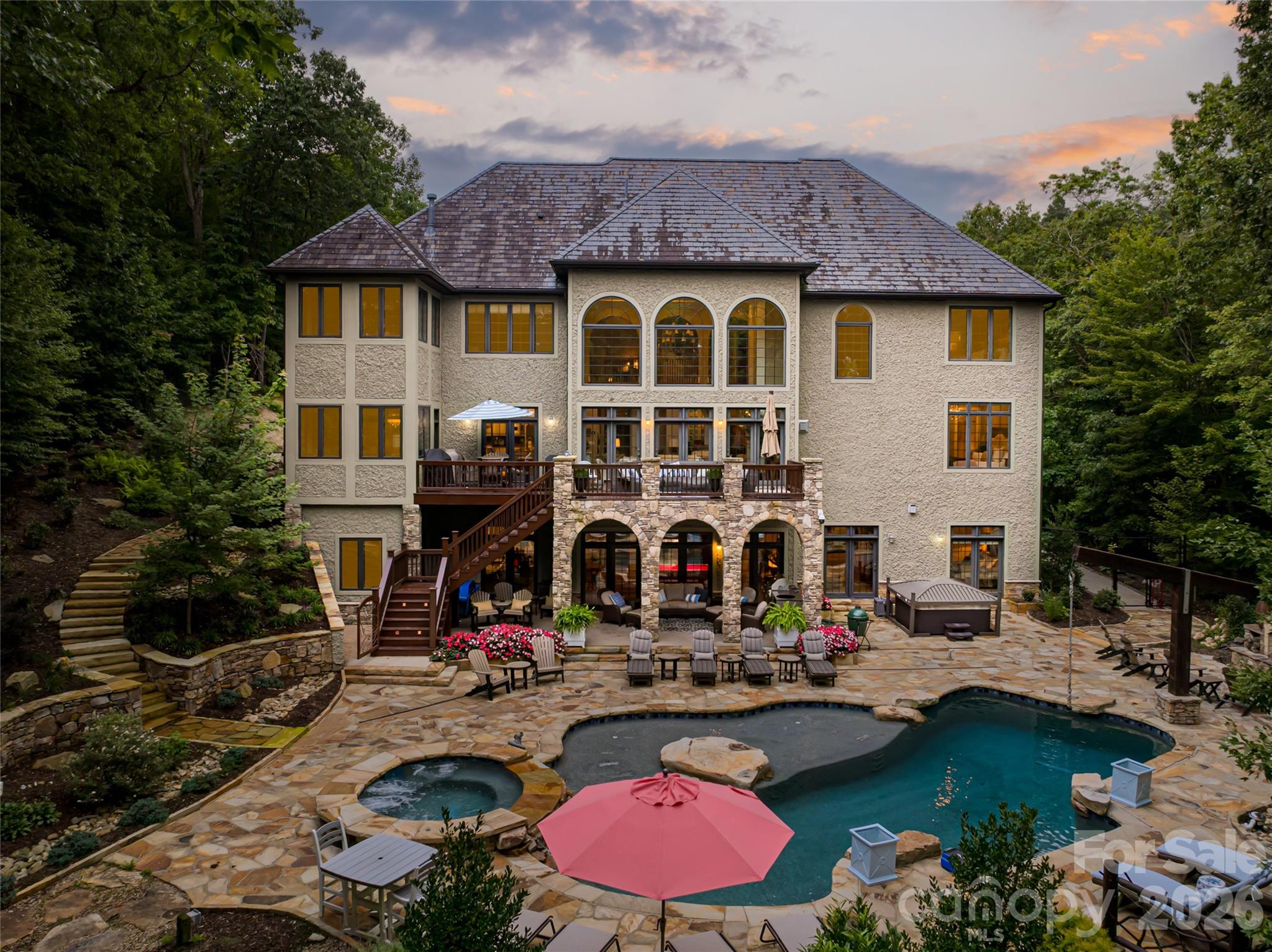 Behind the gates of prestigious Poplar Ridge, this exceptional residence blends timeless elegance with elevated modern living. Impeccable craftsmanship is showcased throughout, from soaring tray and coffered ceilings to graceful arched openings and rich Brazilian cherry flooring. Designed for effortless entertaining and everyday comfort, the open main level centers around a gourmet kitchen featuring custom cabinetry, premium appliances and a generous walk-in pantry. A sunlit breakfast area and sophisticated formal dining room provide welcoming spaces for intimate mornings and memorable gatherings alike. Upstairs, the luxurious primary suite offers a retreat, complete with a fireplace and a spa-inspired bath designed for relaxation and renewal. Additional bedrooms and flexible living spaces provide versatility for guests, remote work or recreation. Outside, the property unfolds into a private resort-style setting with a sparkling pool, expansive terraces, hot tub and fire pit surrounded by lush landscaping and refreshing mountain air. Within one of Asheville’s sought-after gated communities, this distinguished Poplar Ridge estate delivers a lifestyle of sophistication, privacy and comfort.