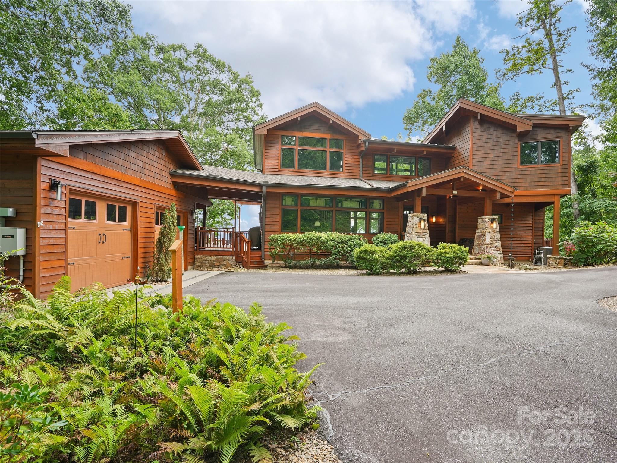 Nestled at a breathtaking 3,800-foot elevation within the prestigious Avalon community, this luxurious post-and-beam residence, custom-crafted by Lindal Cedar Homes in 2012 (design #40844), is a masterpiece of craftsmanship, blending timeless craftsman-style elegance with modern innovation across 4,000 square feet of meticulously designed living space. Sited on a secluded 2.6-acre estate enveloped in total privacy, the home’s commanding 22-foot wall of floor-to-ceiling windows unveils sweeping 15-mile vistas of Western North Carolina’s iconic landmarks—Mt. Pisgah’s soaring peaks, Cold Mountain’s rugged silhouette, and Lake Junaluska’s shimmering expanse—framing Richland Valley in a breathtaking panorama that shifts with the seasons. Approaching via the private 450-foot asphalt driveway, flanked by twin lighted stone pillars hinting at the grandeur beyond, the exterior’s western red cedar cladding and dry-stack stone pillars supporting a dramatically lit canopy exude rustic sophistication, ensuring seclusion as the home remains invisible from the street. Stepping through double 8-foot mahogany doors, the main level unfolds as a haven for living and entertaining, with engineered tongue-and-groove wood flooring optimized for a 5-zone radiant floor heating system, paired with an all-season HVAC and 1,000-gallon propane tank for year-round comfort. The great room, the heart of the home, captivates with automated retractable shades modulating light through monumental windows, and a sconce-flanked, floor-to-ceiling stone fireplace (vented propane) that anchors the space with cozy elegance. A curated art collection, including Mark Bettis’ award-winning “Waiting for the Sun,” and stained glass built-ins by Dianne Lee of The Stained Glass Bungalow, alongside designer lighting, infuse every corner with warmth and artistry. The dining area, illuminated by a dimmable stained glass chandelier, features a 10½-foot live-edge redwood table seating ten, perfect for intimate dinners or grand feasts. The gourmet kitchen, with top-tier appliances, custom cabinetry, and a spacious island, flows seamlessly for effortless hosting. The lower level is an entertainer’s dream, centered around a 12-foot South American walnut live-edge wet bar with Swarovski crystal-accented propane fireplace, royal blue tile, Frigidaire appliances, and solid-wood cabinetry (2nd dishwasher & refrigerator located in laundry room). A home theater with a Samsung 60-inch smart TV, with in ceiling audio and turntable, and a royal blue-felt pool table elevate leisure, while custom wine storage adds refined functionality. A 1,000-pound capacity three-floor elevator ensures accessibility, complemented by a Generac generator and a safety system with heat, smoke, carbon monoxide, and water leak nodes monitored centrally, including in the garage. Bedrooms are serene retreats, with the primary suite offering a spa-like ensuite, dual walk-in closets, and balcony views, while additional ensuites provide guest comfort. The utility area houses HVAC, solar hot water storage, LG washer/dryer, and a utility nexus for seamless operations. Outdoors, a cedar deck with a wood-burning fireplace (propane starter) terrace gardens create an idyllic setting, with an oversized two-car garage via a breezeway and cabinetry for storage. Smart home technology orchestrates lighting, climate, and security, with solar features ensuring sustainability. Just minutes from Waynesville, the “Gateway to the Smoky Mountains,” with its charming boutiques and dining, and a 25-minute drive to vibrant Asheville, this home balances seclusion and access. A rare gem in Avalon’s legacy, 2128 Sleepy Hollow is a timeless treasure, crafted to fulfill every desire and destined to enchant for generations.