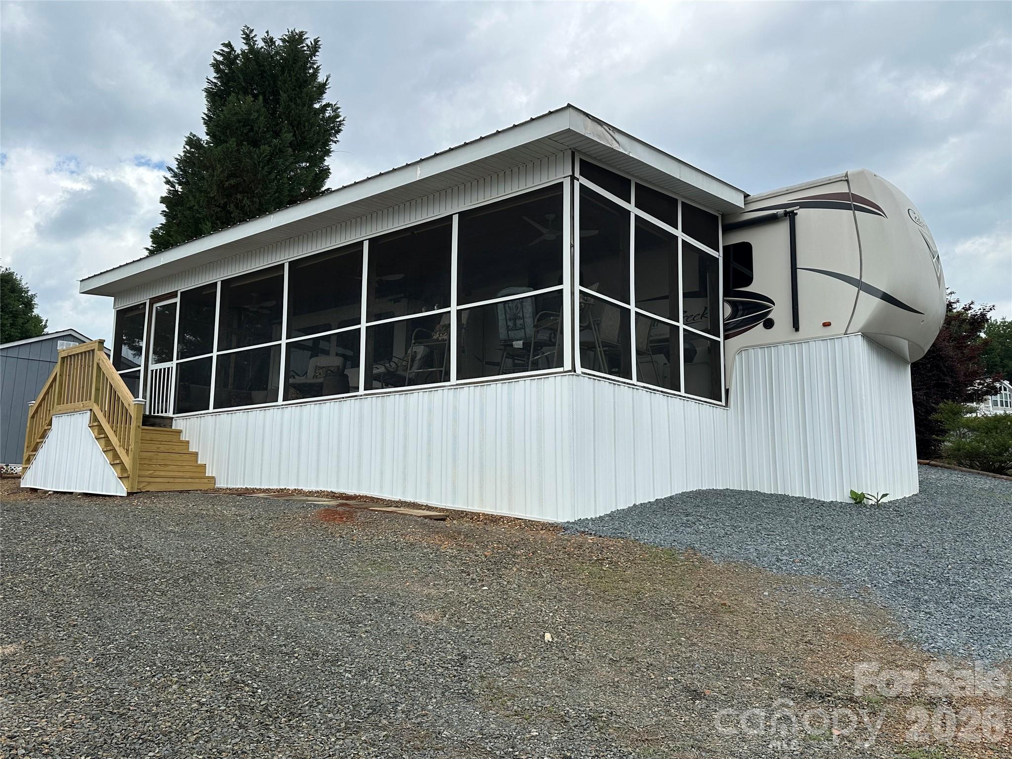 Enjoy lake life at its finest with this 2019 Cedar Creek 2-bedroom plus loft 5th wheel camper offering breathtaking views of beautiful Badin Lake. Relax on the screened porch while watching boats cruise across the water and take in stunning sunsets over the iconic train trestle spanning the lake.
Inside, you’ll find high ceilings, modern furnishings, a cozy electric fireplace, full-size stainless-steel refrigerator, step-in shower, and abundant storage throughout. Recent updates include new underpinning and updated steps, adding both comfort and curb appeal. Located within the gated waterfront community of Badin Shores Resort, this property offers access to an impressive list of amenities just a golf cart ride away, including a swimming pool, basketball courts, putt-putt golf, sandy beach, waterfront boardwalk, clubhouse, and more. Whether you’re looking for a weekend retreat or the perfect vacation getaway, this lakefront escape is ready to enjoy.