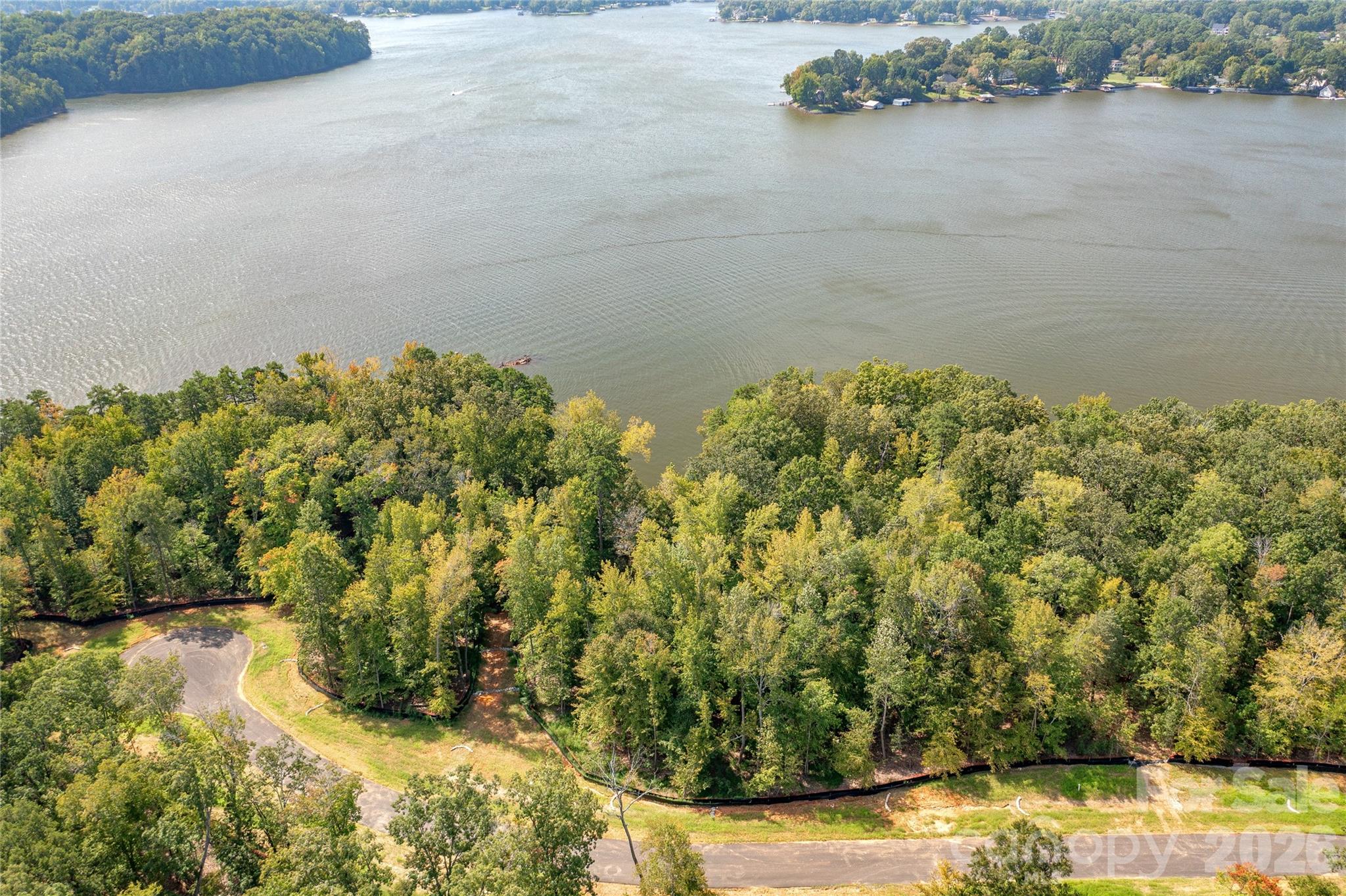 Waterfront homesite 25 offers long southern views of the main channel of Lake Wylie. Located in the South Carolina section of McLean South Shore, this level homesite is located on Great Egret, at the cul-de-sac, which is one of the best streets for views and privacy. Homesite 25 features a point with a natural beach and 489 feet of lake shoreline to call your own! Nestle your pool toward the point and you can take in the sunshine and incredible main channel lake views. Enjoy South Carolina property taxes at this location too! Bring your home plan to reality with one of our talented approved builders. McLean South Shore offers a clubhouse, outdoor pool, playground, walking trails and a fitness room. McLean is located in the southern section of Belmont where you can access the Carolina Thread Trail which wraps around the lake. You may also enjoy year round activities at the Daniel Stowe Botanical Garden with their ponds, walking trails, dog park, and Trailhead Store with beverages and snacks. Just a short drive into the town of Belmont which features restaurants, coffee shops, Stowe Park where you can enjoy the playground, concerts and other festivities. There is even an active train you can sit and watch. Going to events, restaurants and shopping in greater Charlotte NC is only about 30 minutes away. Want to go somewhere farther away - just a short drive to the Charlotte Douglas International Airport. Bring your waterfront dream to reality in McLean South Shore - come see for yourself the amazing the available homesites!