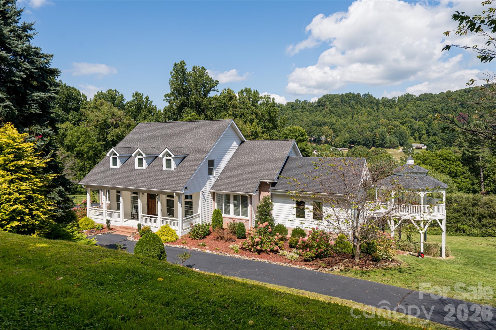 A rare mountain estate in Haywood County, this beautifully reimagined residence blends timeless elegance with modern comfort across 6.74 private acres. Sweeping mountain views unfold from every level, creating a serene retreat just three miles from Waynesville Golf & Country Club, boutique shopping and downtown Waynesville. The light-filled main level is designed for gracious living and entertaining, with updated family and dining spaces flowing into a formal living room. At the heart of the home, the chef’s kitchen features Bosch appliances, an induction cooktop, double ovens, and thoughtful details that elevate form and function. The primary suite is a peaceful sanctuary with a sitting area and spa-like bath. Upstairs, two bedrooms share a Jack-and-Jill bath, complemented by a spacious recreation room. The daylight walkout lower level offers a fully equipped second living space with kitchen, bedroom, bath and flexible rooms, ideal for guests or multigenerational living. A three-car garage and carriage house apartment add versatility. Outdoors, decks, gazebo and landscaped grounds invite year-round enjoyment. Private yet convenient, this exceptional estate offers refined mountain living at its finest.BRAND NEW ROOF.