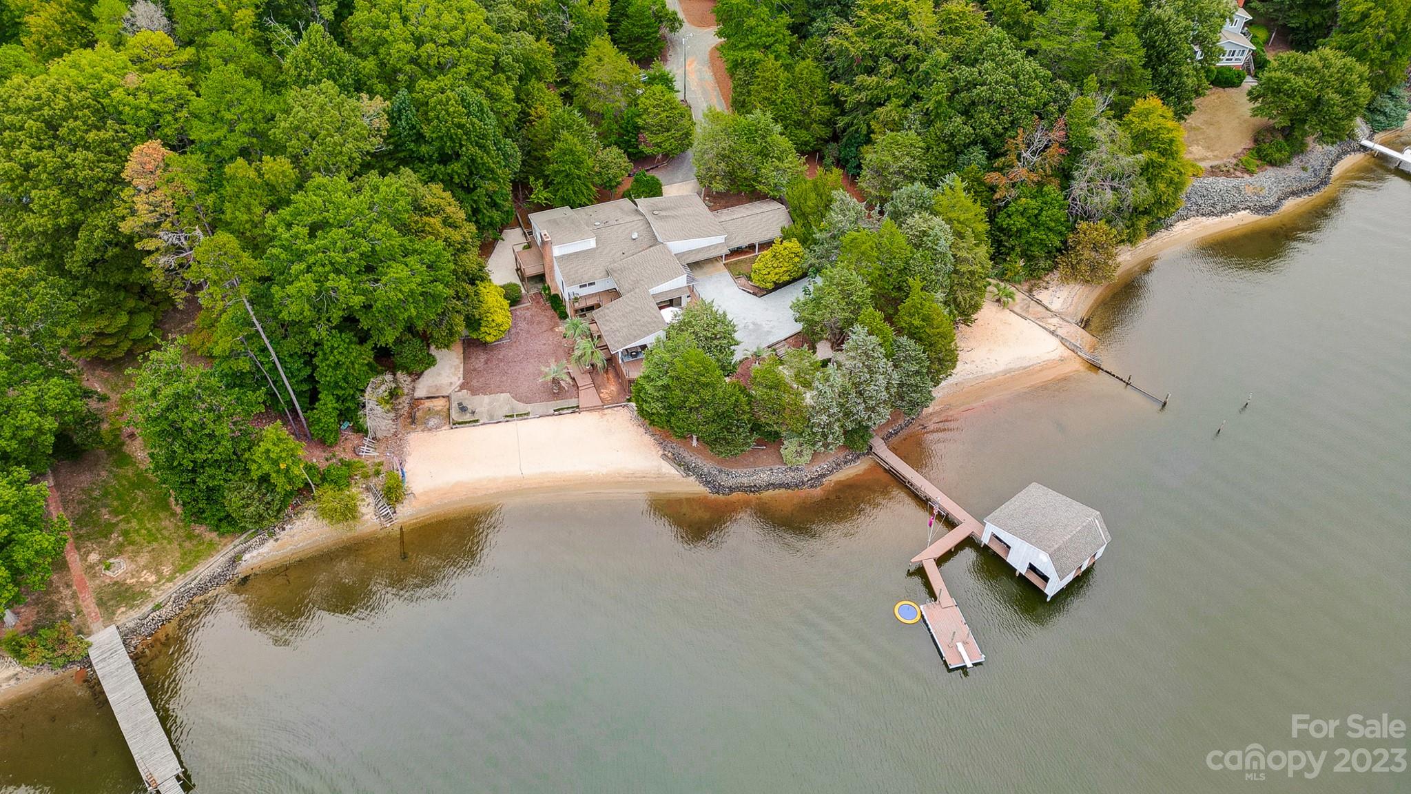Looking for tranquility & relaxation? Find it in this thoughtfully built lake home featuring a gentle sloping lot with spectacular long range views of Lake Wylie.  Separate guest house-perfect for tenants, guests, or home office w/ den, kitchen, 1 bed & 1 bath. The main house is designed to capture the glorious views & boasts a bright & open floor plan, spacious great room, dining area, & gourmet kitchen w/ SS appliances, double oven, & breakfast bar. Lower level provides entertaining space w/ large rec room, bar, fireplace, & exposed beams. Lower level primary suite w/ spa-like bath, 2nd laundry, & access to backyard oasis. Live outdoors on the covered porch or sprawling decks. Launch your kayak or canoe from your private beach.  Large boat house w/ 2 lifts & floating swim dock. There is even a paved boat launch! Make this amazing property your permanent home or rent out when not in use.  Get away from it all, yet live close to shopping, dining, Uptown Charlotte, and airport.