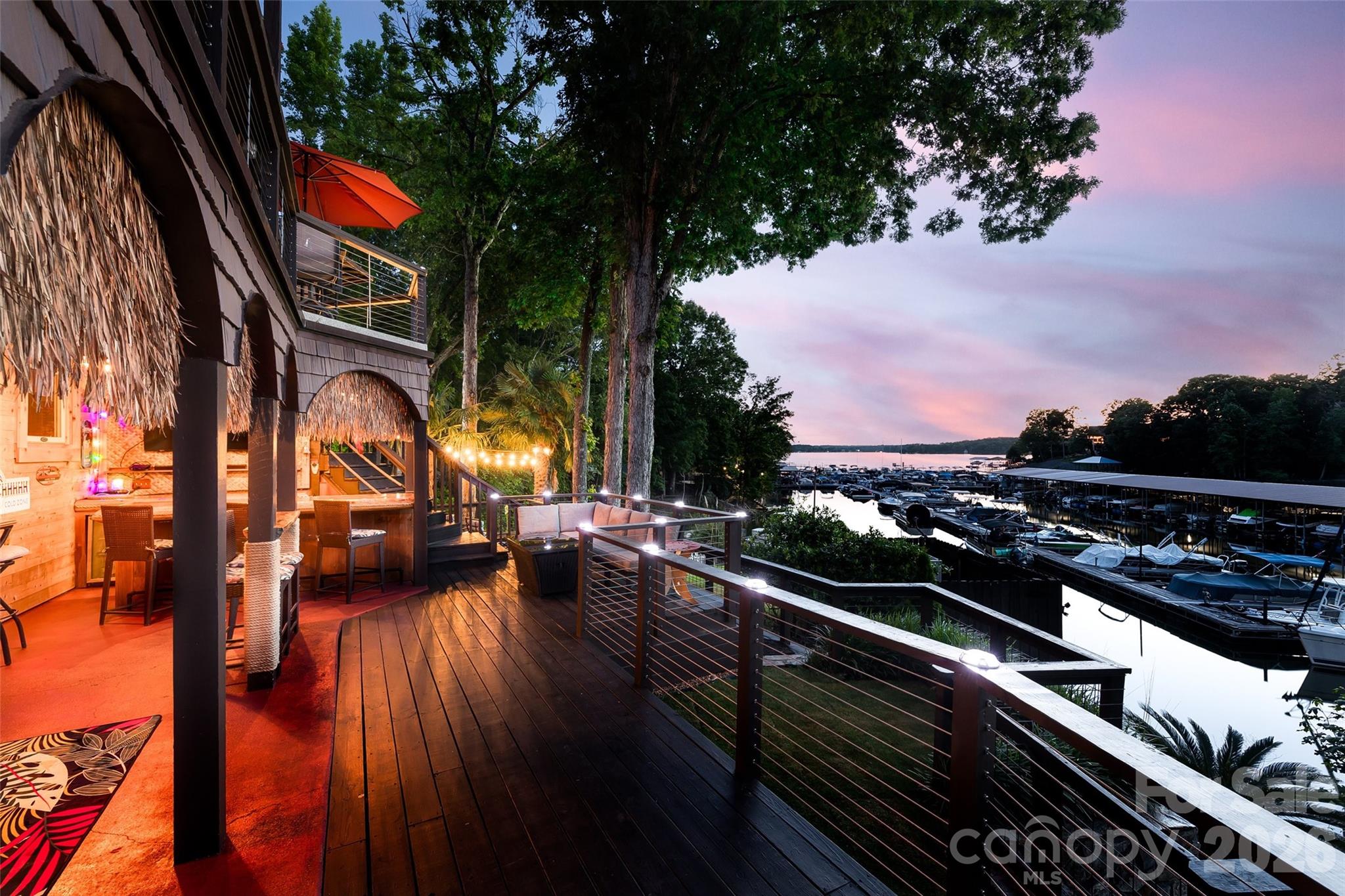 Enjoy breathtaking sunset views over Lake Wylie from this stunning waterfront retreat. Designed for both relaxation and entertaining, the outdoor spaces feature a Barefoot hot tub, a custom-built bar, and 3 levels of deck space, with sleek cable railings to maximize the view. The backyard also includes a stone fire pit, a fenced lawn area with a rock retaining wall, and a PERMITTED private dock with durable composite decking. Inside, the same level of thought and care is evident throughout, highlighted by a complete kitchen remodel featuring custom wood beams and high-end plank Pergo flooring that extends across the main level. The primary suite offers a private deck and a beautifully redesigned spa-like bathroom, complete with an expansive walk-in shower and soaking tub, river rock accents, skylight, and dual vanities. The walk-out basement provides abundant natural light and includes a fully remodeled bathroom with luxury shower. With extensive updates throughout, this home is truly move-in ready. Video tour: https://www.youtube.com/watch?v=XufO7SpdI9w
