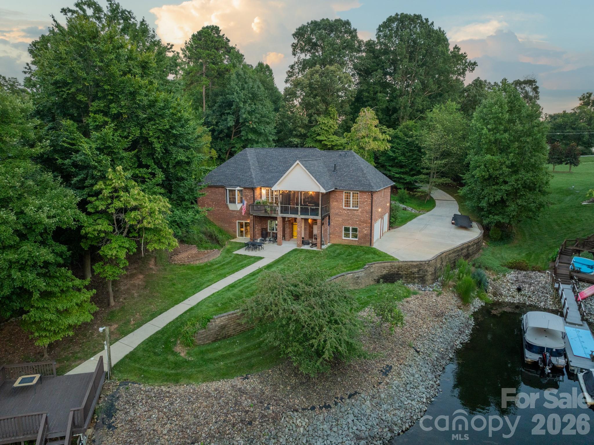 Set on one of the most picturesque deep-water lots on Lake Norman, this custom owner-built full brick waterfront estate offers an exceptional blend of luxury, privacy, and lakefront living. Nestled within a quiet no-HOA community where short-term rentals are permitted, this property presents a rare opportunity for both personal enjoyment and investment potential.

Thoughtfully positioned in a private cove with immediate access to the main channel, the home showcases a beautifully dredged shoreline, an impressive engineered retaining wall, and a gentle approach to the water’s edge — creating an ideal setting for year-round enjoyment on the lake.

Designed for elevated outdoor living, the property features lake-fed irrigation, a custom dock and expansive deck with boat lift, dual driveways, and exceptional parking capacity. The boat is also available for purchase separately.

Inside, the meticulously maintained residence offers generous living spaces with four spacious bedrooms, a large bonus room above the garage, a walk-out basement, and a screened porch perfectly positioned for peaceful waterfront views. The recently renovated owner’s suite bath delivers a spa-inspired experience with a luxurious oversized walk-in shower.

Car collectors, hobbyists, and boating enthusiasts alike will appreciate the rare six-car garage capacity, complete with a Tesla charging station and a fully insulated workshop/auto bay featuring poly-steel construction with impressive R-50 insulation performance. The workshop also includes a convenient half bath, sediment filtration systems, and water softening equipment.

Additional highlights include a spacious recreation area with pool table included, a 2024 roof, and countless thoughtful custom details throughout. Septic permit is for three bedrooms; home is currently configured as four bedrooms.

A truly exceptional waterfront retreat offering craftsmanship, functionality, and the lifestyle Lake Norman is known for.