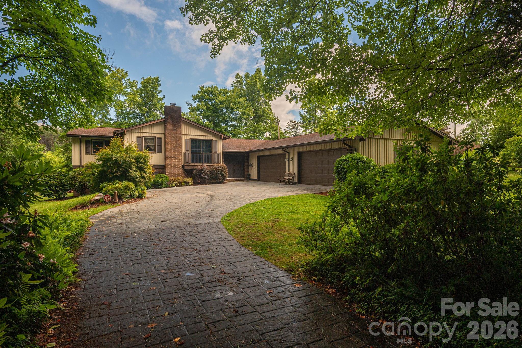 Nestled on two lots totaling 1.2 acres this spacious split level home is a peaceful retreat. Tucked away in a private setting surrounded by a gently flowing creek bordered by ferns you have your own private oasis to relax and unwind in the comforts of home. Property features a 4 car garage plus a detached 2 bay workshop/garage with one bay heated and cooled and another garage in basement. The home offers nearly 2500 heated square feet of living space with 4 bedrooms and 3 full baths. Features foyer, living room, dining room and a kitchen with a breakfast area that has sliding doors open to covered porches overlooking a water garden. The Primary bedroom includes an impressive 15X12 closet offering ample space for wardrobe and organization. Basement has fireplace with gas logs family room/flex space, office and bedroom with bathroom. Updates include roof ,HVAC, windows and vinyl siding, Offering privacy, space and a truly unique outdoor setting makes this property a rare find. Convenient location and only a few minutes away from Lake Hickory's public access. $444,900