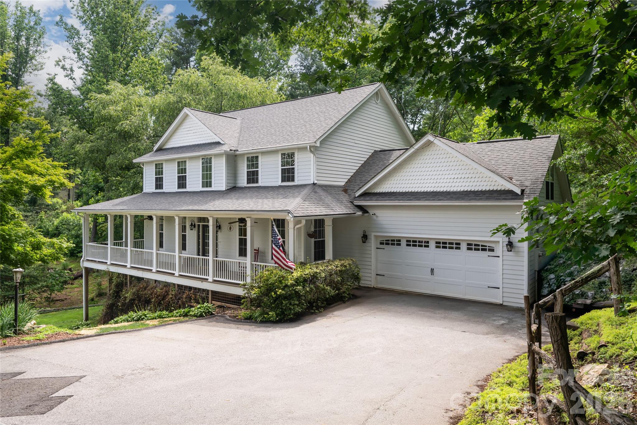 On a rare double lot with future investment potential, this farmhouse-inspired home offers exceptional flexibility, abundant outdoor space and multiple levels of living designed to accommodate a variety of needs. A classic wraparound porch, perfect for rocking chairs, morning coffee and quiet evenings, welcomes you home and sets the tone for the relaxed lifestyle found throughout the property. The beautifully updated kitchen serves as the heart of the home, featuring large windows overlooking the backyard and neighborhood pond, a spacious center island, abundant cabinetry, generous pantry storage and ample workspace for gathering and entertaining. The flowing floor plan connects the kitchen, living room and den, where two gas log fireplaces create warm and inviting gathering spaces. A formal dining room and breakfast nook offer additional options for everyday meals and special occasions. The main-level primary suite provides a convenient one-level living option with a walk-in closet and en suite bath with a garden tub, double vanity and large walk-in shower. The lower level features a fully equipped in-law suite with interior and exterior entrances, including a full kitchen, living area, full bath and bonus room ideal for an office, studio or fitness space. Upstairs, you'll find three bedrooms, two full baths and an oversized bonus room with a half bath, offering endless flexibility. Outdoors, expansive garden areas, established trails and a picturesque fern-lined creek create a private natural retreat. The combination of usable land, flexible living spaces and future potential makes this a unique offering. All of this is conveniently just minutes from the shopping, dining, entertainment and amenities of Biltmore Park.