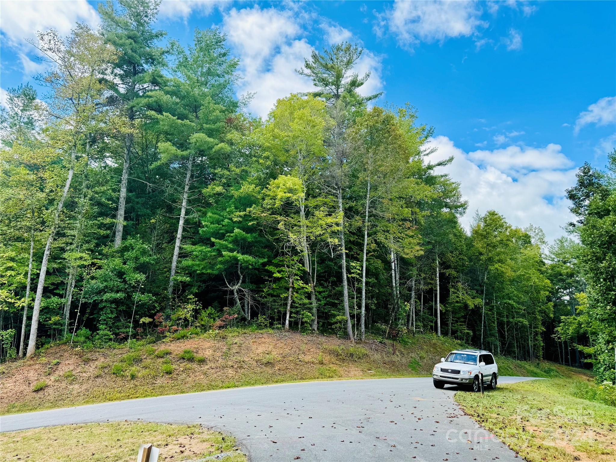 10+ acre lot on Husbands Creek at The Coves Mountain River Club. 3 secluded build sites with beautiful mature hardwoods. Lot is on both sides of Round Mountain Pkwy. Paved driveway to 1 of the build sites. Close to new Equestrian Center and pickle-ball courts. The Coves is a Firewise USA® Community, a program of the National Fire Protection Association, that helps neighbors organize to reduce wildfire risk, harden homes, and create defensible space by managing vegetation and preparing for wildfires. Community trail easement crosses property on lower side near creek. The Coves is a 3,200 acre gated community in Blue Ridge Mountains of North Carolina. The mountain-top clubhouse has pool, hot-tub, fitness center, and 360° views of the Blue Ridge, South Mountains, and Brushy Mountains. 5 miles of Johns River on site to kayak, fish, or pan for gold. Community trail system to hike, bike, UTV, ride horses. 2 equestrian centers. Dog park. Pickle-ball courts. Community vineyard and gardens. Clubs, classes, activities, excursions, cook-offs. No time limits to build. 1 hr 15 mins to Charlotte or Asheville. Minutes to Blowing Rock, Morganton, Lenoir NC, Pisgah National Forest, Blue Ridge Parkway. Lender/Builder info available.