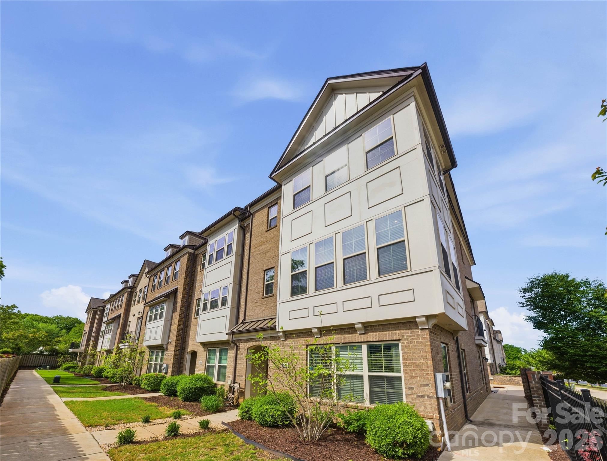 Luxury end-unit townhome in the heart of Madison Park, just steps from Park Road Shopping Center, Montford Drive and the light rail with easy access to Uptown. Located in an intimate community of only 38 brick townhomes built in 2019, this nearly new residence offers the perfect blend of style, space and convenience. Spanning three levels, the home features an attached two-car garage with epoxy flooring, a main-level en suite bedroom and two spacious suites on the upper level. Thoughtfully designed with 9-ft ceilings throughout, LVP flooring, stainless steel appliances and an open-concept layout ideal for modern living. Your gourmet kitchen boasts a large island, pantry and flows seamlessly into the living and dining area. Oversized sliding glass doors lead to your private balcony. Both upper-level suites offer generous walk-in closets and well-appointed bathrooms with walk-in showers. The primary suite includes a unique versatile flex space ideal for home office, gym or to build out more closet space. An exceptional home to own nearly new construction in one of Charlotte's most desirable and walkable locations.
