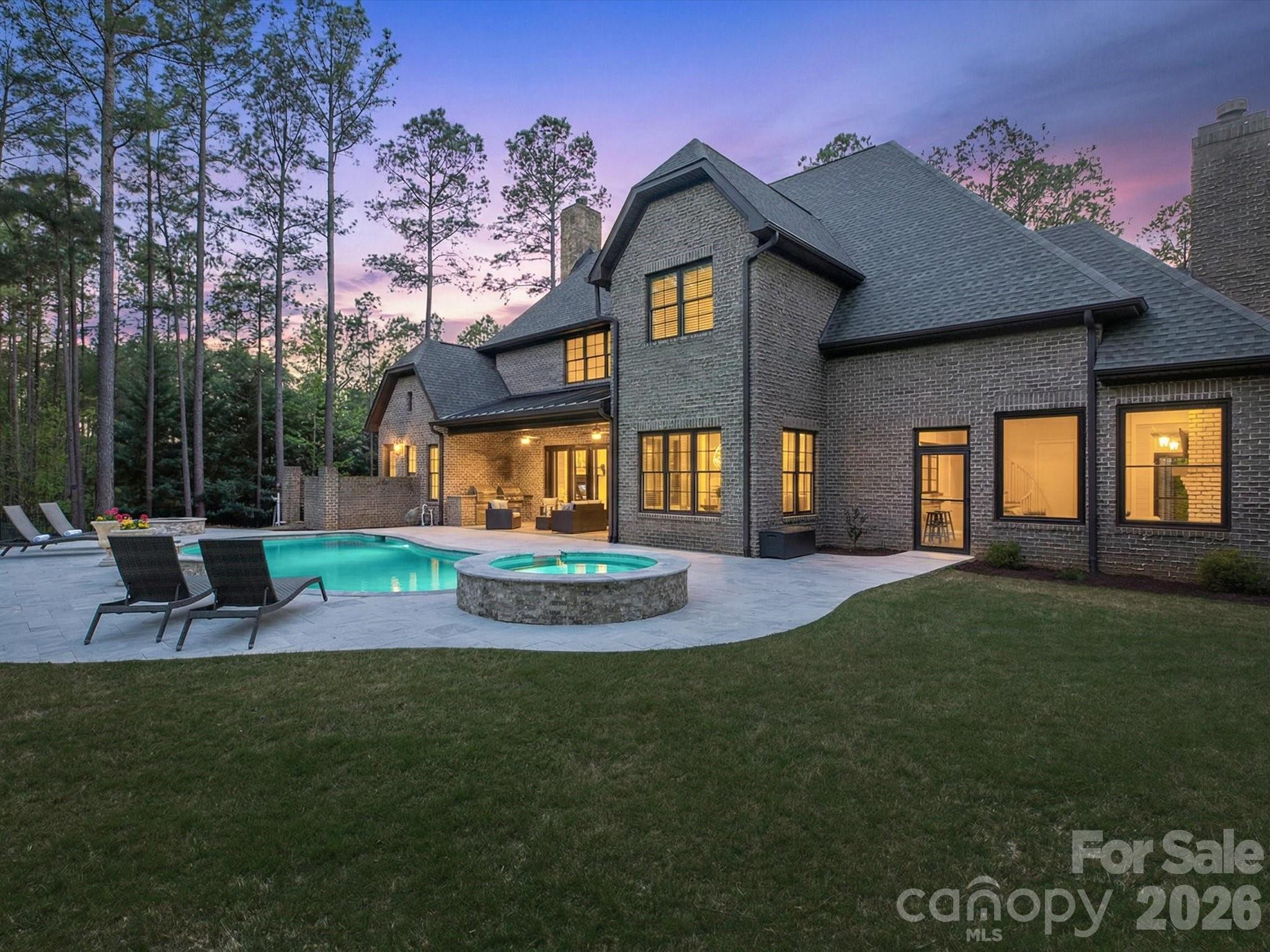Welcome to this stunning custom home in the highly sought-after Trinity Ridge, where luxury and thoughtful design meet everyday comfort. The primary retreat on the main level offers a true spa-like experience, featuring a spa shower, private outdoor patio, and a serene sitting area—your own personal escape. The bright gourmet kitchen is the heart of the home, seamlessly connecting to a sun-drenched sunroom, perfect for morning coffee or relaxed gatherings. Spacious secondary bedrooms and expansive social areas provide plenty of room for entertaining and everyday living. Rich hardwoods, heavy moldings, and exquisite millwork elevate every space with timeless elegance. Step outside to your private outdoor oasis, complete with a heated saltwater pool with waterfall, covered porch with built-in charcoal and gas grills, cozy fire pit, and extensive professional landscaping—ideal for year-round enjoyment and unforgettable entertaining.
