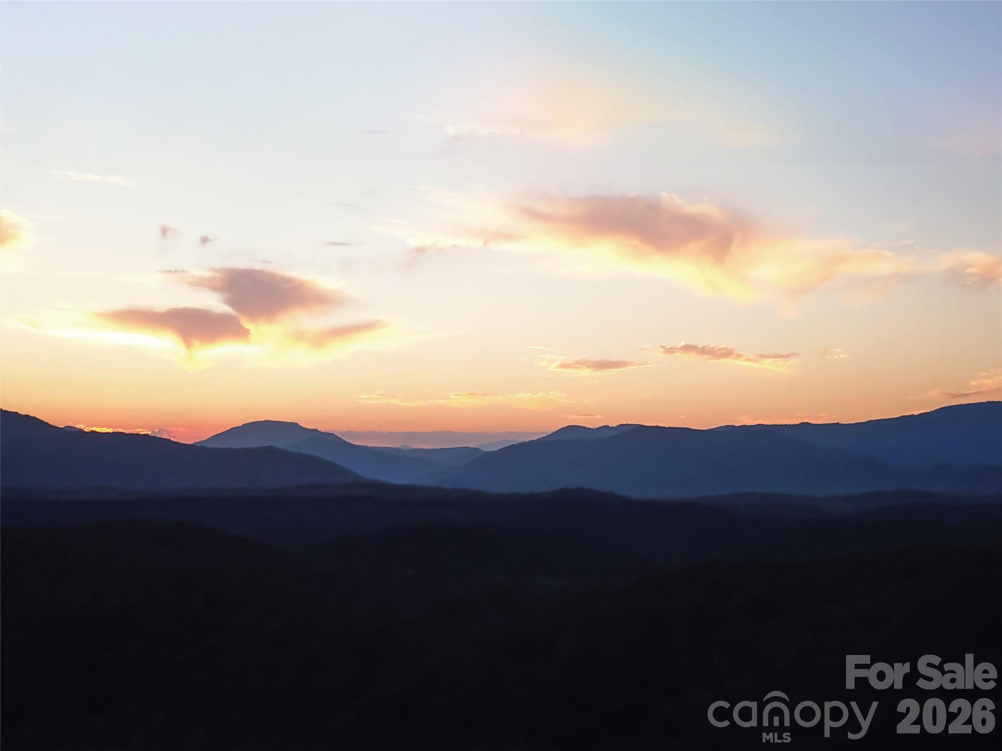 This private 13.41-acre parcel sits in a quiet gated community with underground utilities and easy paved access. Although secluded, it’s only ten minutes from Lake Lure, Chimney Rock, and the Broad River for quick access to an incredible range of outdoor recreation.

The land features a mature hardwood forest, scattered pines, and a naturally open understory that makes the acreage fully walkable. You’ll find mountain laurel, wild azaleas, dogwoods, seasonal chanterelle mushrooms, and beautiful rock outcroppings throughout the land, with abundant wildlife enhancing the quiet, natural setting.

A gentle, build-ready homesite offers 180° winter views with potential for year-round expansion. Nature trails wind through the acreage, and two simple firepit areas provide spots for sunsets, stargazing, and relaxing by the cascading stream. The stream traces the full length of both lots, adding movement, sound, and a calming presence across the property.

Overall, it’s a private, walkable mountain sanctuary offering exceptional possibilities.