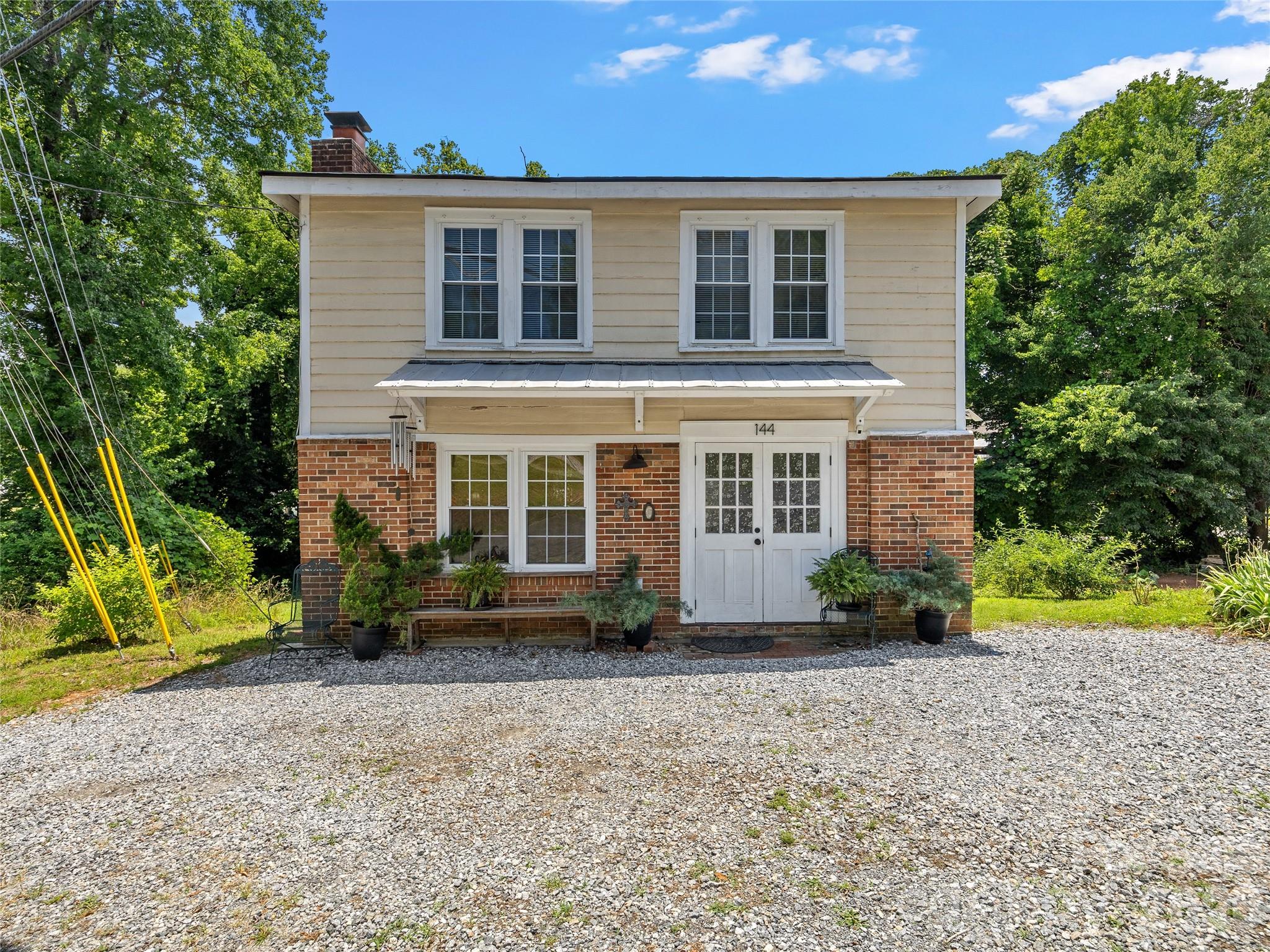 Located in the heart of downtown Tryon, this charming 1930s home offers the rare opportunity to live, work, invest or do a little of all three. Just steps from local restaurants, galleries, shops and community events, the location is hard to beat. The property is also positioned near the proposed Saluda Grade Trail, a planned rail trail connecting Tryon, Saluda, and Zirconia that is expected to become one of the region's premier outdoor amenities. Inside exposed wood beam ceilings, hardwood floors, and abundant natural light create a warm and inviting atmosphere. The main level features an open living and dining area, kitchen, half bath, and french doors leading to a spacious rear deck overlooking the backyard. Upstairs you'll find two bedrooms including a generous primary bedroom with fireplace along with a full bath and laundry area. Outside the large deck with pergola provides the perfect spot for morning coffee or evening gatherings. A seasonal creek and off-street parking add to the appeal. The roof was replaced in 2020. CBD zoning, City Water and Sewer, natural gas heat and central air this property offers exceptional flexibility as a primary residence, rental property, office space, or live/work opportunity in one of Western North Carolina's most beloved small towns.