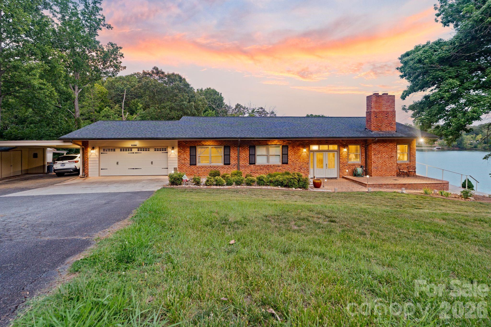 Welcome to 6296 Southlake Drive, where spectacular long-range views of Lake Hickory take center stage. Situated on approximately 1.51 acres, this waterfront property offers an exceptional setting with multiple outdoor living spaces, a private pier, mature landscaping, and countless opportunities to enjoy lake life from sunrise to sunset.

350 Feet of shoreline on the main channel of Lake Hickory!

Designed with entertaining in mind, the split-foyer floor plan offers inviting spaces on both levels, each showcasing incredible lake views. The upper-level living room features crown molding and a brick fireplace, while the adjacent dining area is surrounded by windows and opens through two Anderson sliding doors, installed approximately six years ago, to a side brick patio overlooking the water and a second patio overlooking the backyard and lake. Whether enjoying your morning coffee or hosting friends for dinner, the views provide an unforgettable backdrop.

The beautifully updated kitchen combines style and functionality with quartz countertops, custom cabinetry installed in 2006, a breakfast bar, pantry, recessed lighting, and a picturesque view of Lake Hickory from the kitchen sink. Appliances include a wall oven, smooth-top cooktop, microwave, dishwasher, refrigerator, and disposal.

The upper level includes three bedrooms and two full bathrooms. The spacious primary suite overlooks the lake and features crown molding, a ceiling fan, and an updated en-suite bath with granite countertops, a walk-in tile shower, soft-close cabinetry, tile flooring, and linen storage. Additional bedrooms offer generous closet space, ceiling fans, and crown molding.

The lower level creates even more possibilities with a large den featuring a second brick fireplace, an additional dining area with panoramic lake views, and another pair of Anderson sliding doors opening to the covered patio and outdoor entertaining areas. A second kitchen is equipped with Corian countertops, a breakfast bar, pull-out pantry, smooth-top range, refrigerator, and tile flooring, making the space ideal for hosting gatherings or accommodating extended guests. A billiards room, private office with a secure closet and lake views, mudroom, and full bathroom complete the lower level.

Outdoor living is truly the highlight of this remarkable property. Multiple brick patios, a covered patio with a metal ceiling and tiled floor, extensive landscape lighting, and beautifully maintained grounds create inviting spaces to relax or entertain while taking in some of the most impressive views on Lake Hickory. The private pier offers convenient access to the water for boating, fishing, kayaking, or simply enjoying the peaceful surroundings.

Additional features include a two-car garage currently utilized as a workshop, an attached carport, storage space, full-span steel trusses, walnut interior doors throughout, updated window sash balances, two heat pumps, including a two-stage 4-ton 14 SEER system, and a separate 2-ton heat pump serving the bedroom and billiards room areas. 

Properties offering this combination of panoramic Lake Hickory views, thoughtful updates, flexible living spaces, exceptional outdoor entertaining areas, and private waterfront access are truly rare. Don't miss the opportunity to experience one of Lake Hickory's most remarkable settings.
