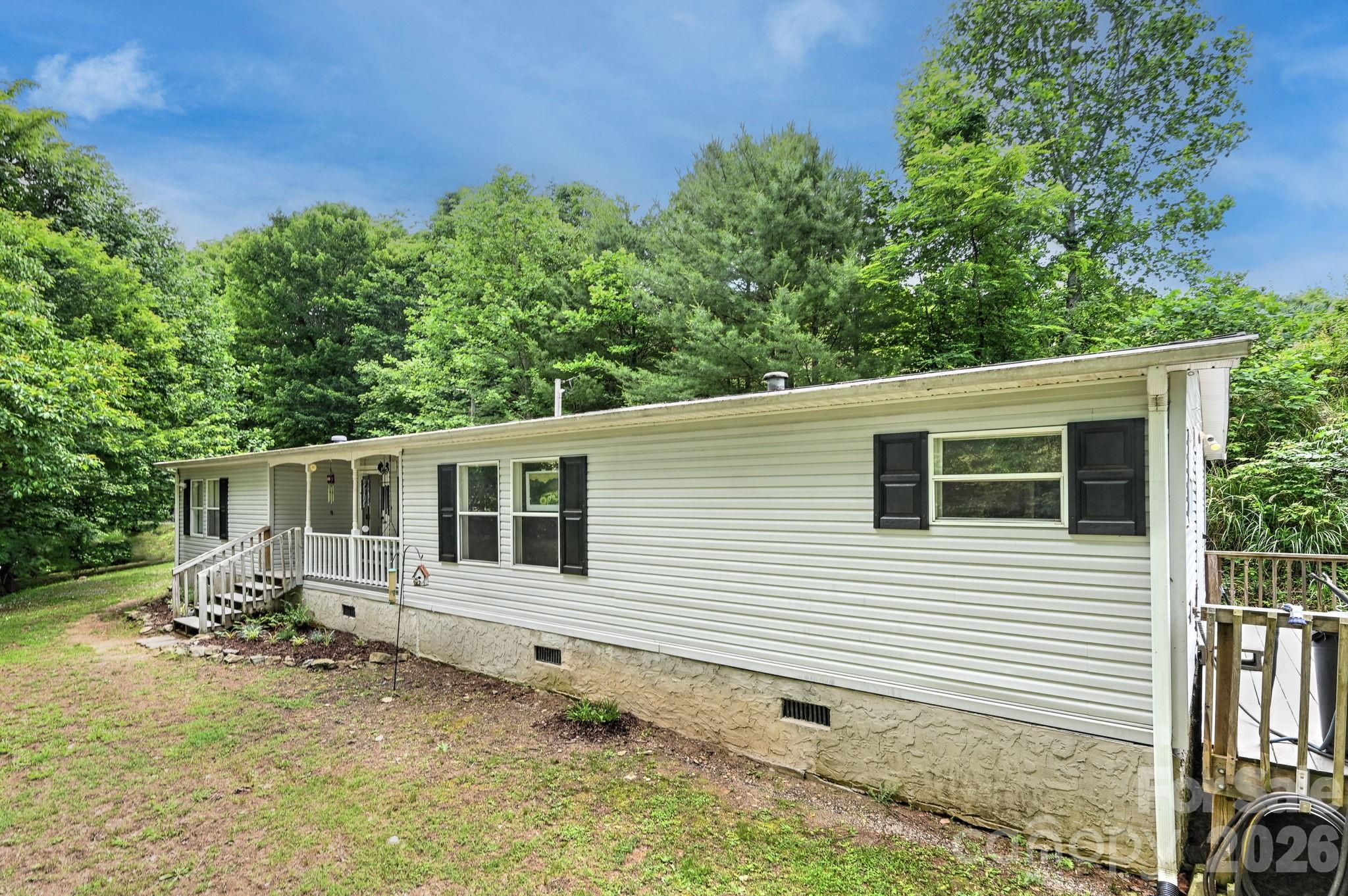 Discover the perfect blend of privacy, functionality, and country charm with this beautifully maintained 3 bedroom, 2 bath home situated on 1.43 private acres. This home is surrounded be peaceful countryside and showcasing long range pastoral views. This property offers the ideal setting for those seeking space, privacy, and rural living. Inside, the spacious living area features a gorgeous rock fireplace, wood-look luxury vinyl plank flooring flowing throughout the living room. The large dining area is perfect for gatherings, while the kitchen offers abundant cabinetry, chair rail molding, custom tile backsplash, and a hidden pet door for your furry friends to access the side deck. The spacious primary suite is designed for comfort and style, featuring double doors leading into the large ensuite bath complete with a soaking tub, double vanities, and a walk-in shower. A split-bedroom floor plan provides added privacy with two additional bedrooms and a full bath featuring a tub/shower combo. The laundry room also includes convenient outdoor access onto the back porch. This property also includes a 10x16 storage building, making it ideal for equipment storage. Conveniently located less than 15 minutes to Mars Hill, Marshall and less than 25 minutes to Weaverville.