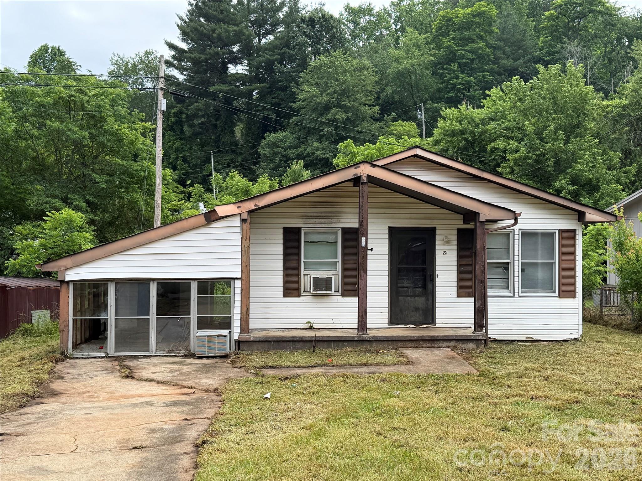 Recently foreclosed, this fixer upper has easy access to Waynesville's cute Downtown area and sits on a level lot with a creek boarding the rear of yard.  3 bedrooms and 1.5 baths with an open kitchen living room floor plan the space feels large and bright. This is a nice starter home but may need significant repairs to qualify for traditional financing As-Is. Washer / Dryer hook up in the hall.  The home was lived in 6 months or so ago and the appliances worked then.   The 252 sqft enclosed Carport is not counted as heated living space but was previous a finished area.  The level yard is bordered in back by a small branch, a fence runs along the right side to the rear.