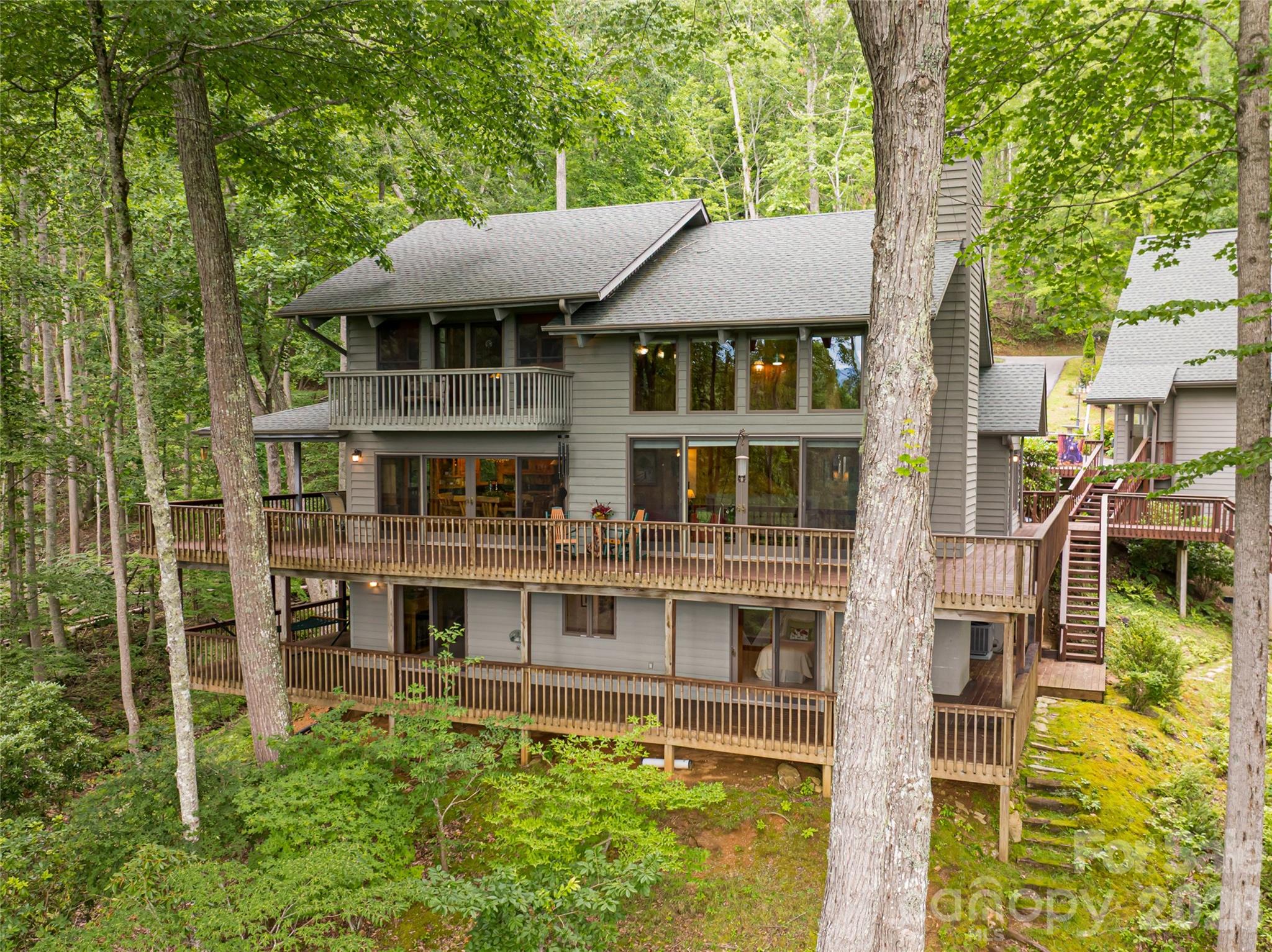 This is the kind of mountain property buyers wait years to find—significant acreage, a true guest house, year-round views, and close proximity to town—all without the isolation or inconvenience typically associated with rural Western North Carolina.

Set on approximately 12 acres just five minutes from downtown Burnsville and within easy access to Asheville, shopping, healthcare, and the Asheville Regional Airport, this property offers the freedom of land ownership with the practicality of a location that supports everyday life. Positioned at a comfortable higher elevation, the home benefits from cooler summer temperatures and long-range Blue Ridge Mountain views, without steep roads or difficult access.

The setting is unmistakably special. A private stream, pond, and integrated water features run through the property, creating a sense of calm and permanence that enhances both the views and the experience of arriving home. This is not a parcel carved from a hillside—it is usable, intentional acreage that invites exploration, relaxation, and long-term enjoyment.

The main residence is designed for how people actually live in the mountains. Three generous bedroom suites, multiple living areas, and warm wood finishes create a home that feels substantial yet welcoming. Over 3,000 square feet of covered and open decking expands the living space outdoors, ideal for entertaining, quiet mornings, and evenings framed by mountain light. The great room serves as the heart of the home, featuring soaring ceilings and a dramatic floor-to-ceiling stone fireplace that opens seamlessly to the dining area and spacious kitchen, all oriented toward the views.

A detached guest house elevates this property into a rare category. Thoughtfully updated and entirely private, it provides true flexibility—perfect for extended stays, multigenerational living, a dedicated work-from-home environment, or hosting without compromise. Properties offering a separate guest residence this close to town are increasingly difficult to replace. Add in the private deck and it's utterly irreplaceable!

A pristine oversized two-car garage with workshop space and an upstairs bonus room adds further utility and future potential, whether for storage, hobbies, or additional finished space.

Private, accessible, and exceptionally well-balanced, this property stands apart in today’s market. It delivers acreage, views, guest accommodations, and proximity in one cohesive offering—an increasingly rare combination for buyers seeking a refined mountain lifestyle near Asheville and the heart of Western North Carolina.