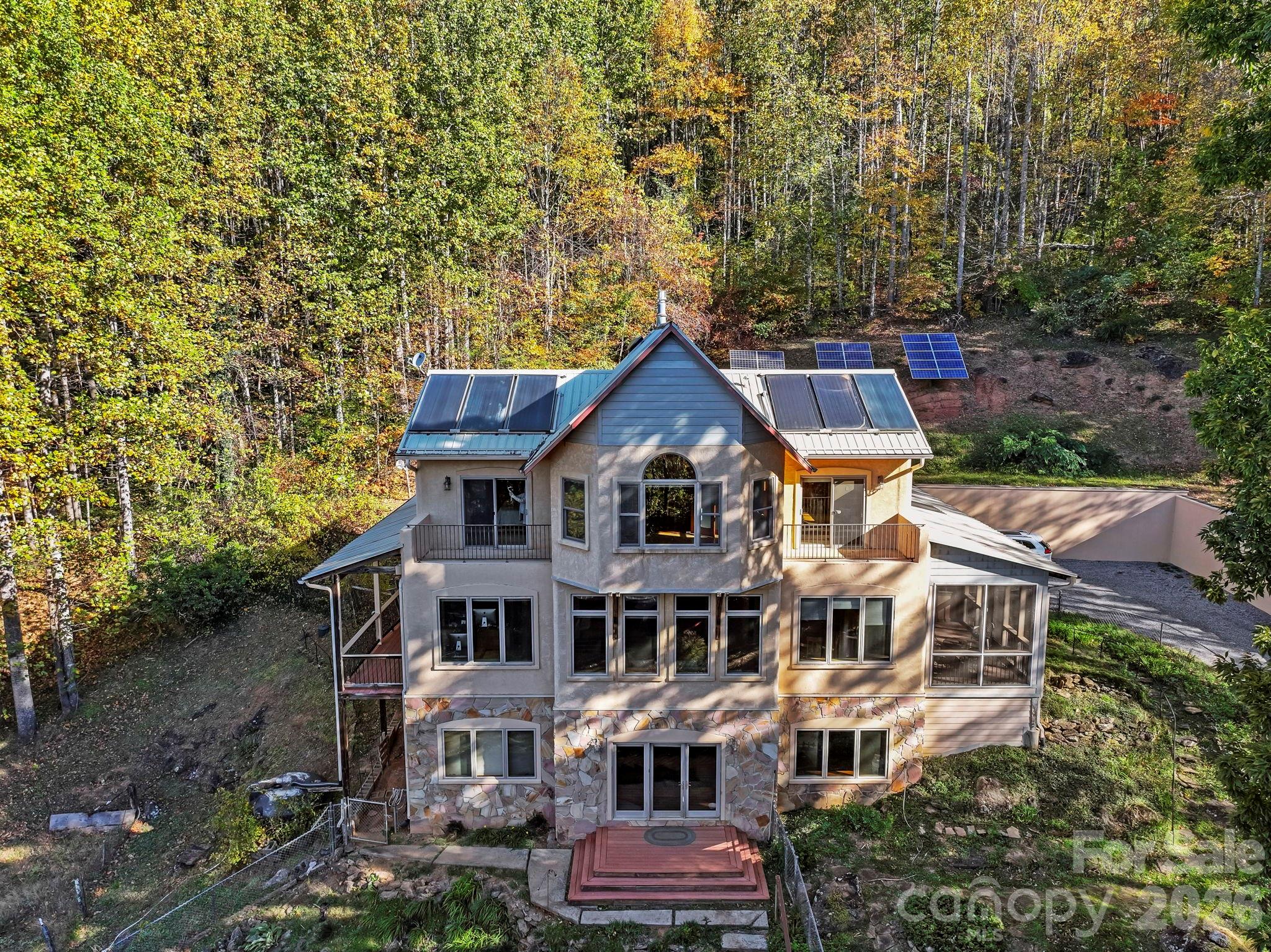 Casa Solara: Embrace Sustainable Mountain Living with Flexible Options Near Black Mountain
Discover a truly exceptional opportunity with Casa Solara, a meticulously crafted off-grid, passive solar home situated on 11 private acres just 4 miles north of vibrant Black Mountain. This rare Western North Carolina gem offers breathtaking long-range mountain views and a lifestyle committed to sustainability without compromising comfort.

Thoughtful Design & Spacious Interiors Spanning 3,868 square feet, Casa Solara presents 3 bedrooms and 3 baths, thoughtfully designed by Alice Dodson and built by Mark Bondurant. The main level is an inviting hub, featuring an open-concept living area, kitchen, and study. Here, radiant floor heat, a cozy propane stove, unique curved architectural walls, and expansive windows bathe the space in natural light while framing stunning views. Upstairs, two serene bedrooms open onto a private balcony, sharing a spacious bath, alongside a bright, versatile yoga or sunroom. The walk-out lower level offers additional flexibility with a bedroom, bath, media room, bonus space, and a dedicated utility/battery room.

High-Performance Living with Future Flexibility Built for optimal performance, Casa Solara's south-facing orientation maximizes passive solar gain, complemented by 12-inch concrete walls (R-17) that provide exceptional thermal mass and natural climate control. The robust off-grid system includes a 3.6 kW photovoltaic array, Outback inverter, 48 industrial batteries, and solar thermal for hot water and radiant heat, all backed by a Kohler propane generator. A private well and 3-bedroom septic system are also in place.

For those seeking adaptable living, it's important to note that traditional grid electricity can be brought to the property, offering enhanced flexibility. An estimate detailing the cost for this connection is available in the attachments, providing clarity for future planning.

An Outdoor Haven for Self-Sufficiency The expansive grounds support a self-sufficient lifestyle, boasting terraced gardens, a substantial 1,550-gallon rainwater collection system for irrigation, and established fruit trees including peach, Asian pear, and persimmon. Additional structures enhance functionality, with a dedicated woodworking shop, a practical storage cabin, and a charming chicken barn. The property also presents the potential for additional homesites, offering further investment or development opportunities.

Casa Solara is more than a home; it's a sanctuary for those who value beauty, performance, and a conscious connection to nature, with the added benefit of future-proofing options. Discover this unparalleled blend of sustainable design and modern comfort.
