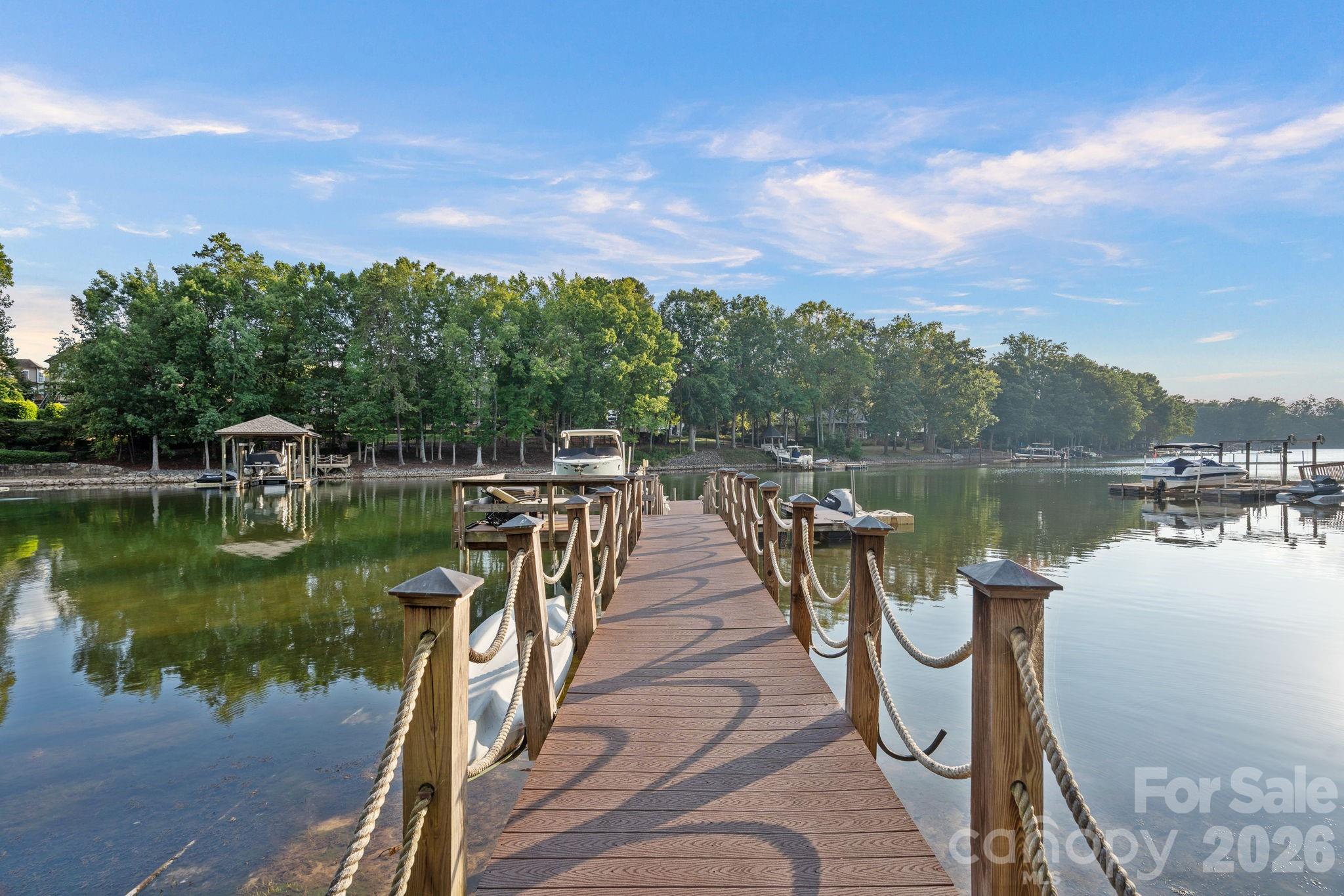 Nestled within the exclusive enclave of Wright's Emerald Cove, the European-inspired neighborhood of custom-built homes, this Lake Norman residence offers an unmatched blend of elegance, privacy, and resort-style living. Set on a 1.24-acre wooded lot, the home features five bedrooms, four ensuites, and a spacious bonus room. The main-level primary suite is a private retreat with an oversized spa bath, while the gourmet kitchen boasts a large island, gas range, double ovens, and an expansive walk-in pantry. High-end finishes are showcased throughout, with a full-house generator providing peace of mind. The backyard is a true oasis, highlighted by a heated saltwater pool with spa, dramatic fire bowls, a poolside cabana complete with grill, refrigerator, and sink, and an inviting outdoor fireplace. The property’s private dock with lift, additional boat slip, and jet ski pads ensure effortless enjoyment of Lake Norman’s waters. A three-car garage and meticulously designed grounds complete this one-of-a-kind estate, offering the perfect balance of European charm and modern luxury in one of the lake’s most coveted neighborhoods.