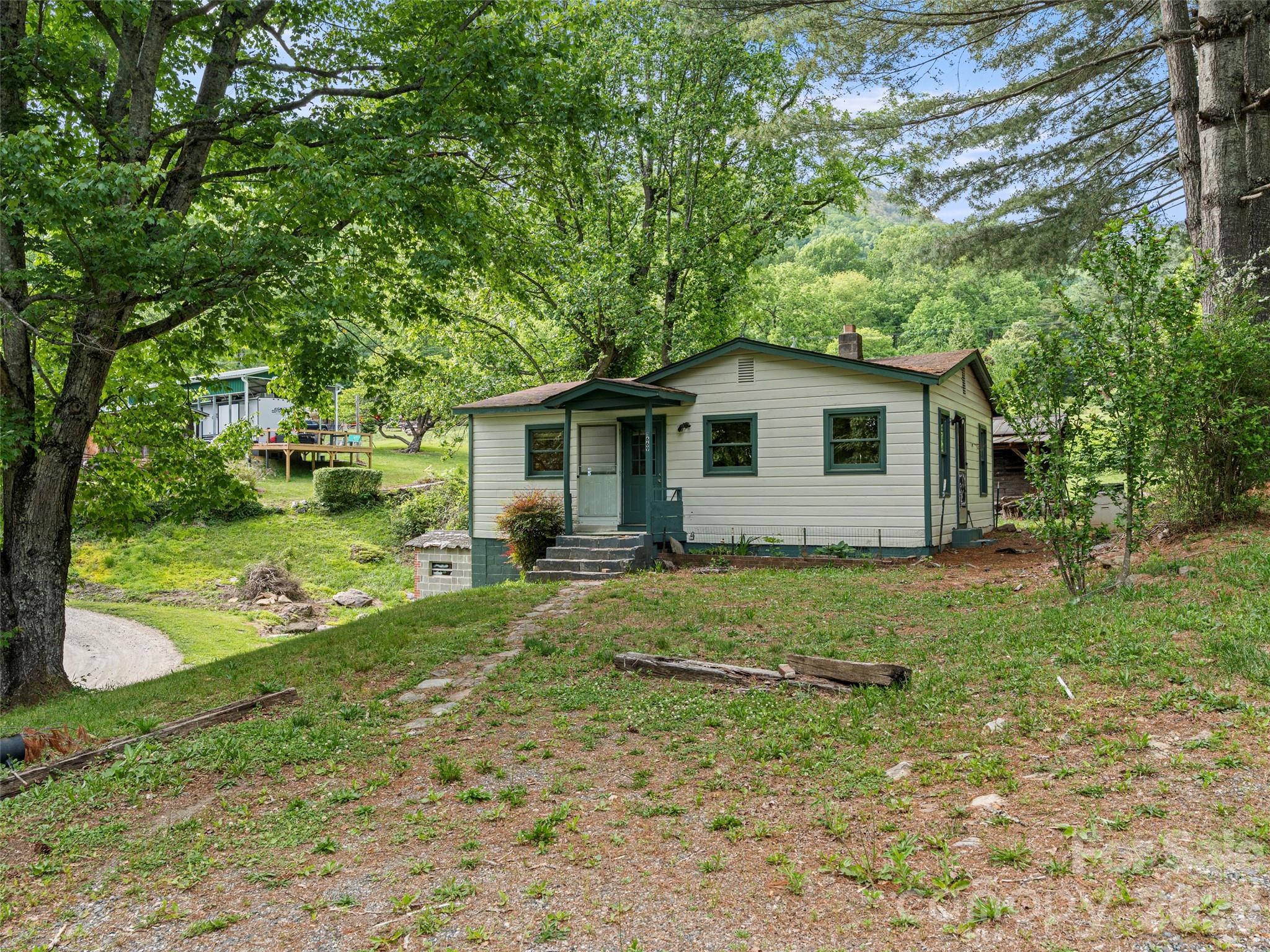 Step into this adorable 1960's bungalow, sitting on just under half an acre with half of it untouched. The 2 bedroom 1 bathroom house was painted in the summer of 2025, and has had some cleaning up of the property. Only 7 minutes to 74, with easy access to the Blue Ridge Parkway as well. Also only a 25 minute drive into downtown Waynesville. Whether you want to remodel the home and resell or build on the other side of the property there are so many options with this lot and so much potential. The home has been vacant for about 3 years but has been looked after.