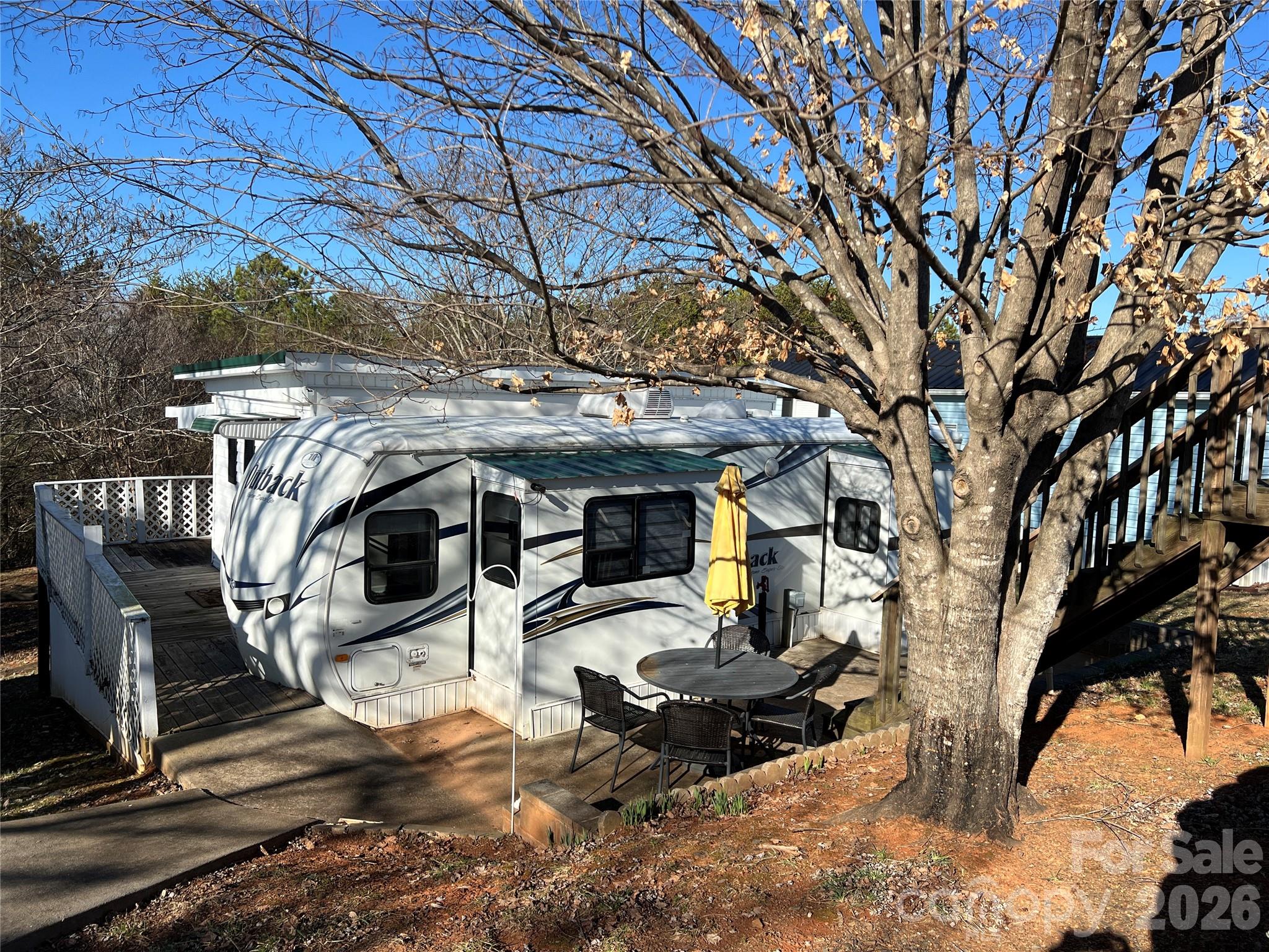 Welcome to easy lake living inside Badin Shores Resort! This charming 2-bedroom, 2-bath retreat offers a combination of a renovated 2011 Outback camper and an addition that was completed in late 2021. This added space provides extra comfort, privacy, and flexibility for guests, family, or full-time living. Enjoy the updated camper with electric cooktop. upgraded counters and breakfast bar. Adding to the appeal, the property backs up to common grounds and wooded areas, creating a peaceful setting where wildlife sightings are frequent and privacy is enhanced. It’s the perfect spot to relax and enjoy the natural beauty that makes lake life so special. 
Located in the gated Badin Shores Resort community on Badin Lake, residents enjoy incredible amenities including lake access, community beach, boat ramp, pier, dock, clubhouse, fitness center, outdoor pool, playground, picnic areas, sport courts, pickleball, recreation areas, ponds, and more. Whether you are looking for a relaxing lake escape, a low-maintenance retreat, or a place to enjoy all that Badin Lake has to offer, this property is a wonderful opportunity. Cash purchase only.