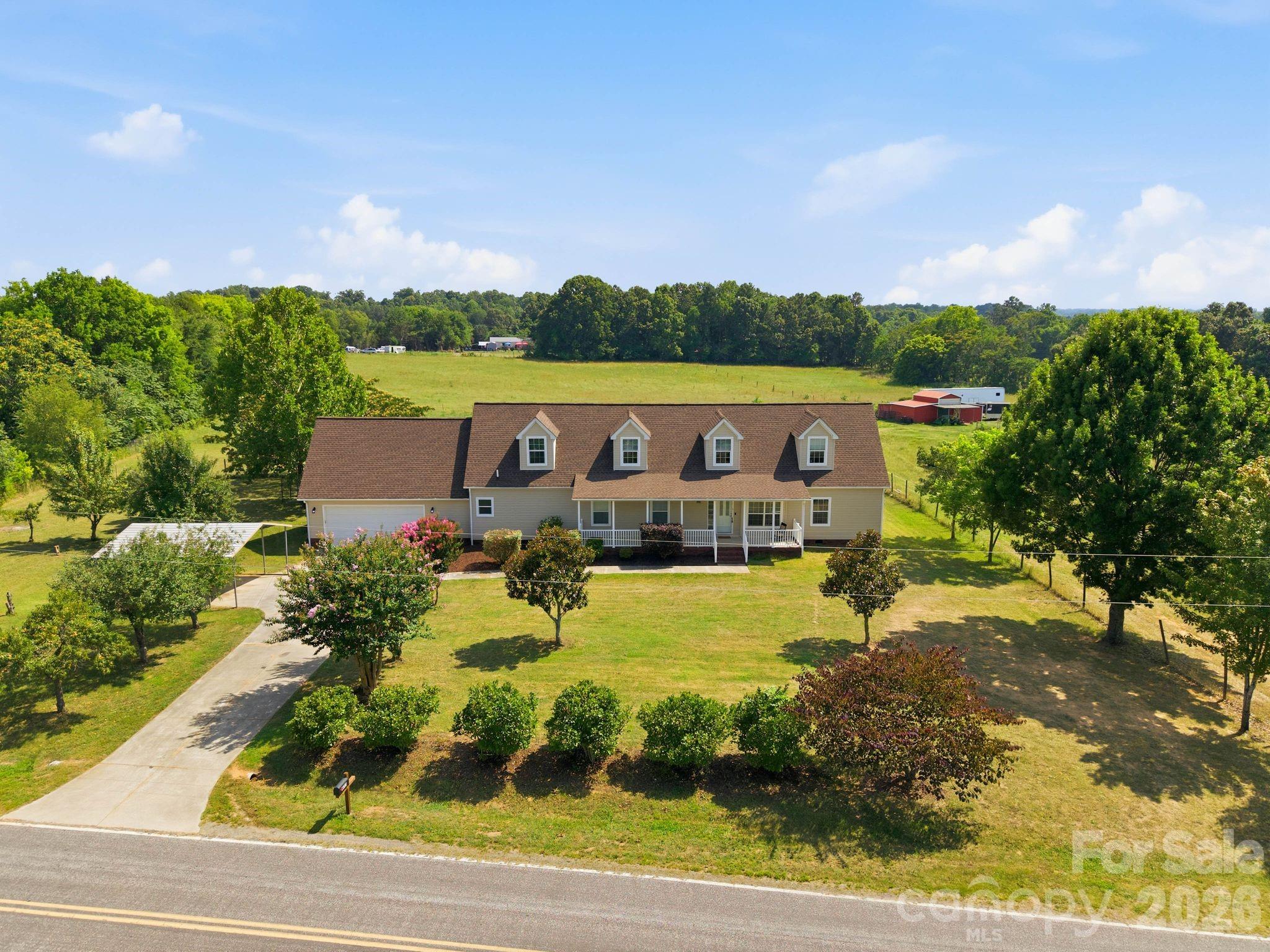 Discover the rare combination of space, flexibility, and peaceful country surroundings on 1.26 acres in Salisbury. Designed for the way people live today, this expansive home offers 5 bedrooms, 5 full bathrooms, multiple gathering spaces, and exceptional versatility for multigenerational living, guests, or hobbies.
A welcoming front porch sets the tone before stepping inside to a sprawling floor plan featuring a spacious main-level primary suite, two additional bedrooms on the main floor, and multiple living spaces that can easily adapt to your needs. The kitchen is equipped with abundant cabinetry and generous workspace, opening seamlessly to the home's comfortable living areas. Upstairs, the private in-law suite offers outstanding independence with its own kitchen, separate exterior entrance, and interior access - ideal for extended family, long-term guests, or private living quarters. Enjoy quiet mornings on the covered back porch overlooking the expansive backyard and scenic neighboring pastures. Completing the property are an attached two-car garage, an additional two-car carport, and the elbow room that only an acre-plus homesite can provide. Offering space to spread out, flexible living options, and a picturesque setting, this is a property that's ready to fit a variety of lifestyles. that's becoming increasingly difficult to find. Rowan County has no completed septic or well records on file, contact Listing Agent for additional information.
