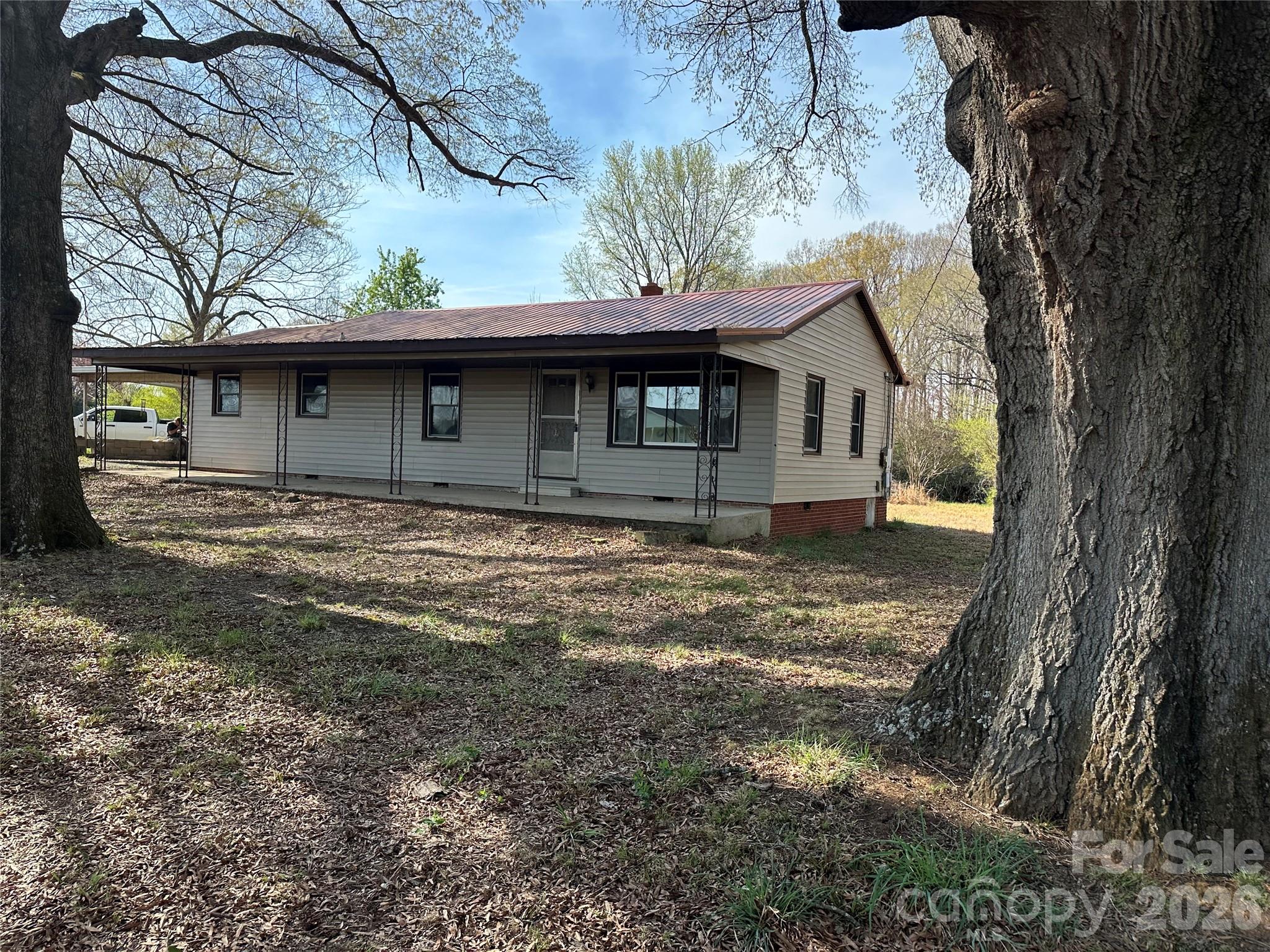 Welcome to country living. This property has a beautiful peaceful setting with a large lot, pecan and fruit trees, 3 buildings of which one is set up as a chicken coup but could be used as a workshop, an attached carport that enters into a mudroom, separate laundry room off the mudroom, open kitchen overlooking the dining/den area, two spacious bedrooms, large living room, and a relaxing front porch. The bedrooms and living rooms have hardwood flooring. This home is move in ready and also has potential for renovation to make it your own.